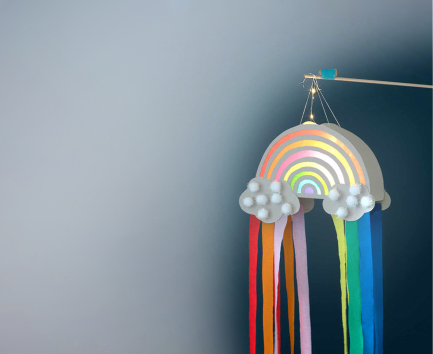 Gebastelte Laterne in Form eines Regenbogens leuchtet vor dunklem Hintergrund