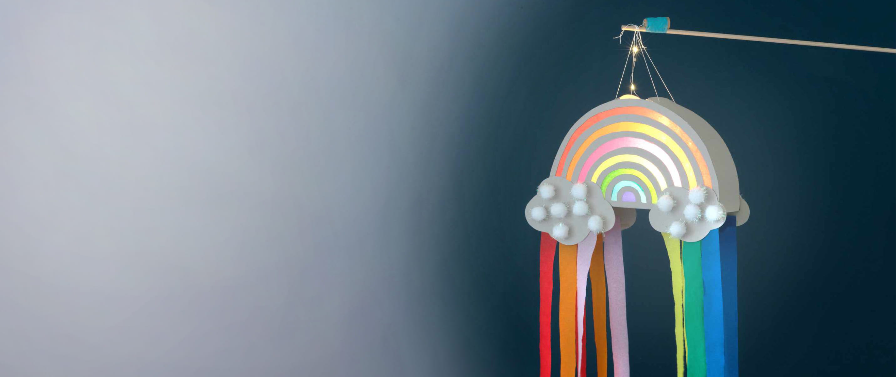 Gebastelte Laterne in Form eines Regenbogens leuchtet vor dunklem Hintergrund