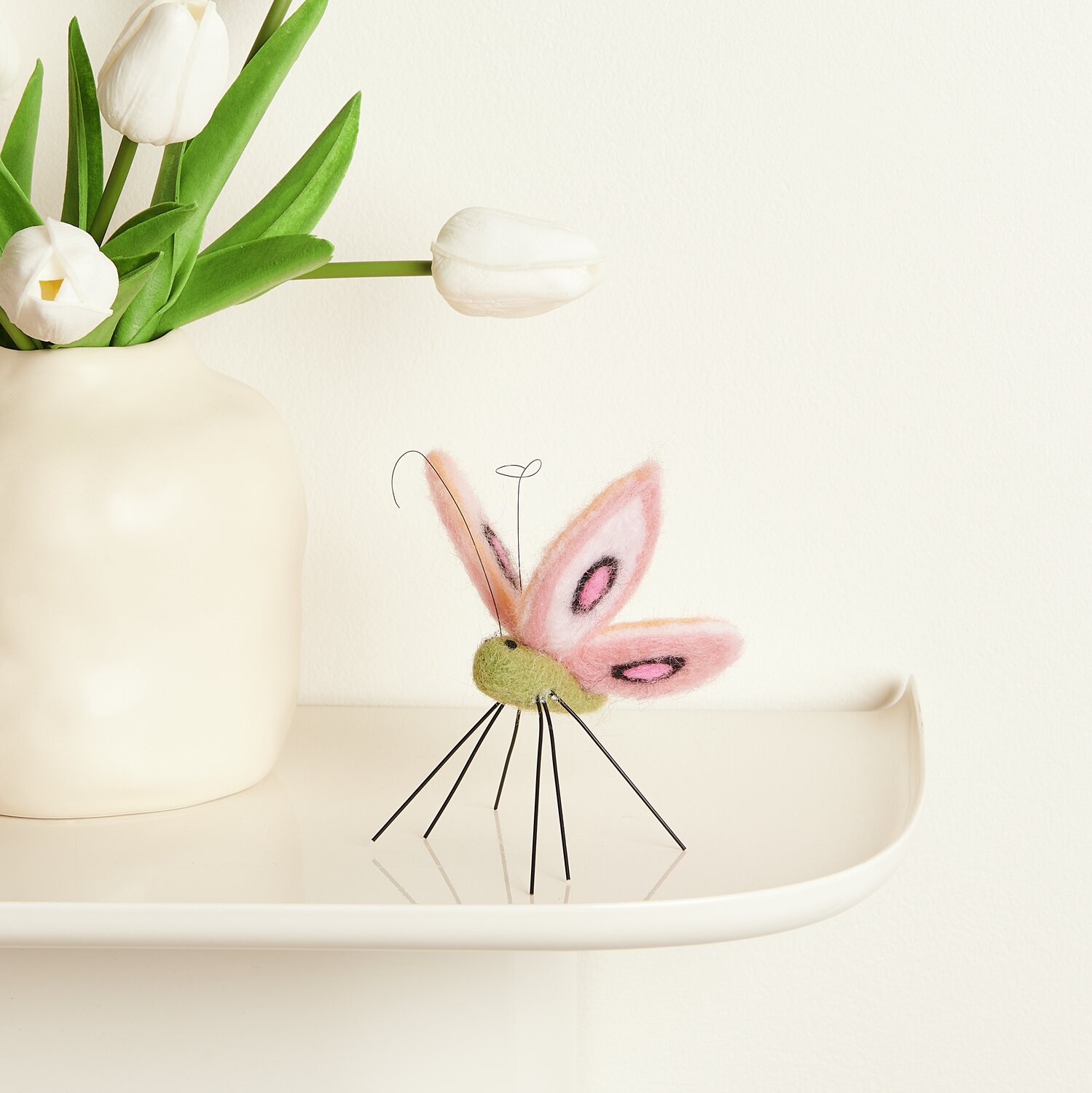 Aufhänger Filz-Schmetterling: Dekorativer Schmetterling aus Filz in Rosa und Grün auf einem Regal.