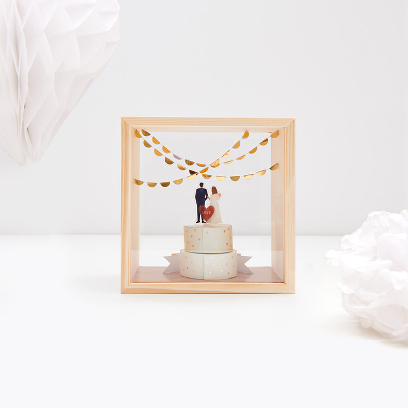 Holzrahmen mit Miniaturfiguren zum Thema Hochzeit