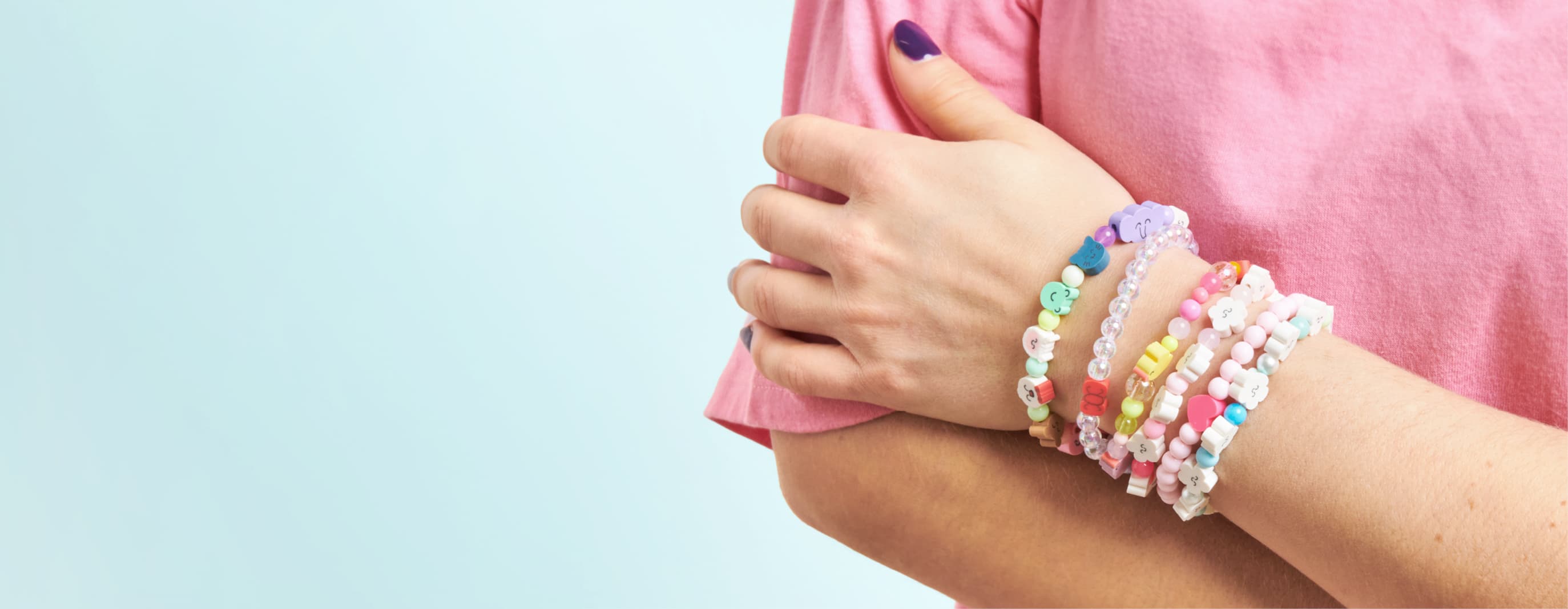 Ein Handgelenk ist mit Armbänder mit bunten Perlen und illustrierten Tier-Perlen geschmückt.