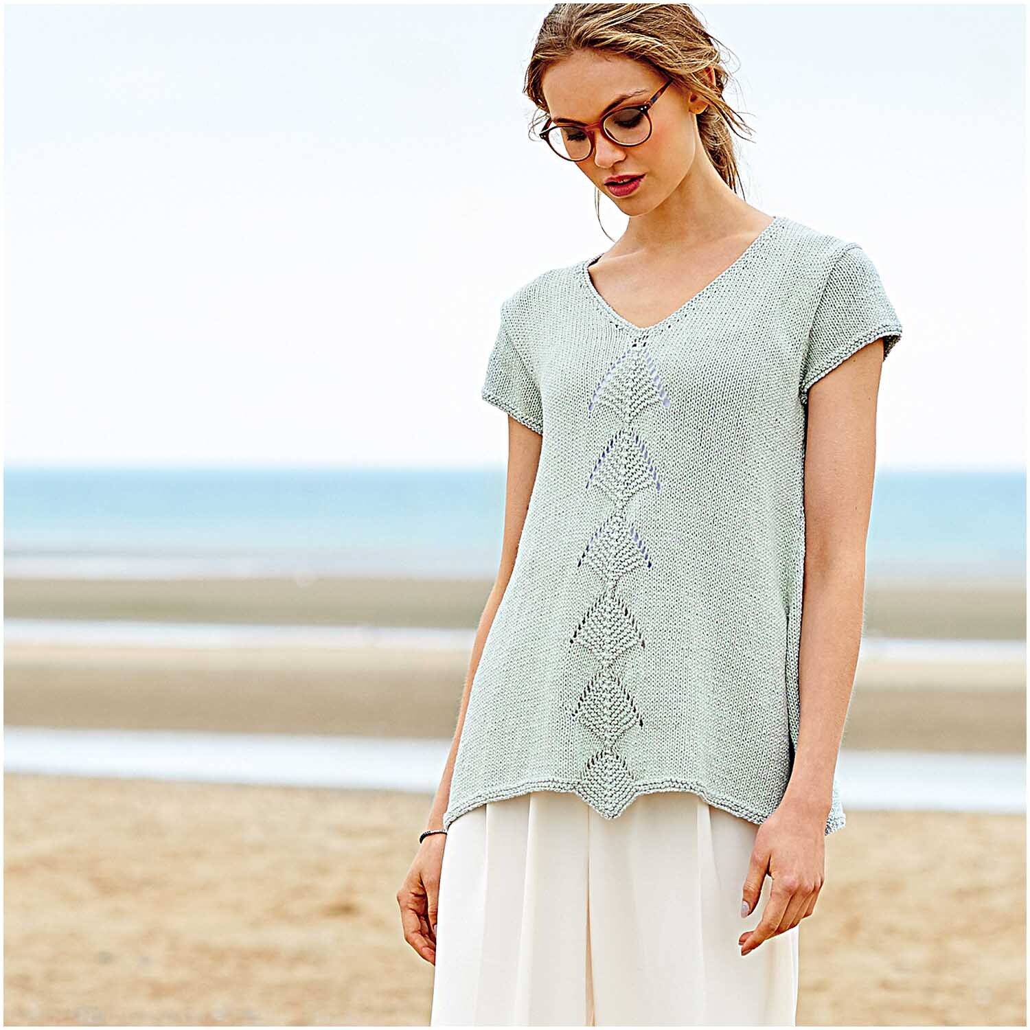 Fashion Cotton Métallisé dk: Frau am Strand in einem eleganten, hellen Strickoberteil von Rico Design.