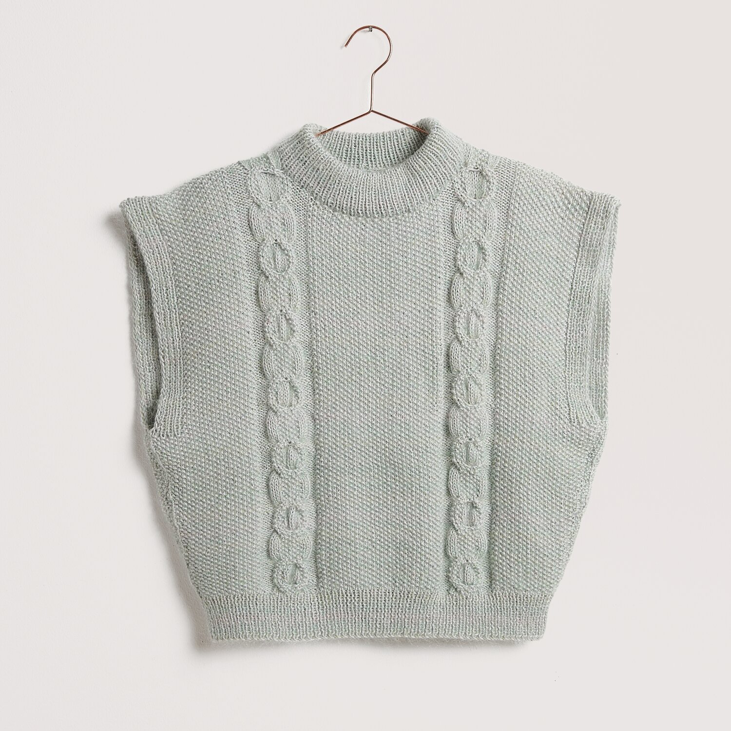 Strickweste in Silbergrau mit Zopfmuster, ärmellos und rundem Kragen, auf einem Kleiderbügel.