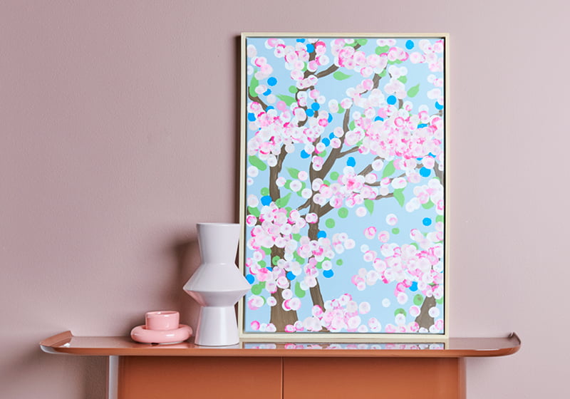 Leinwand mit abstrakten Kirschblüten, gemalt mit Acrylmarkern, ist auf einem Regal wohnlich dekoriert