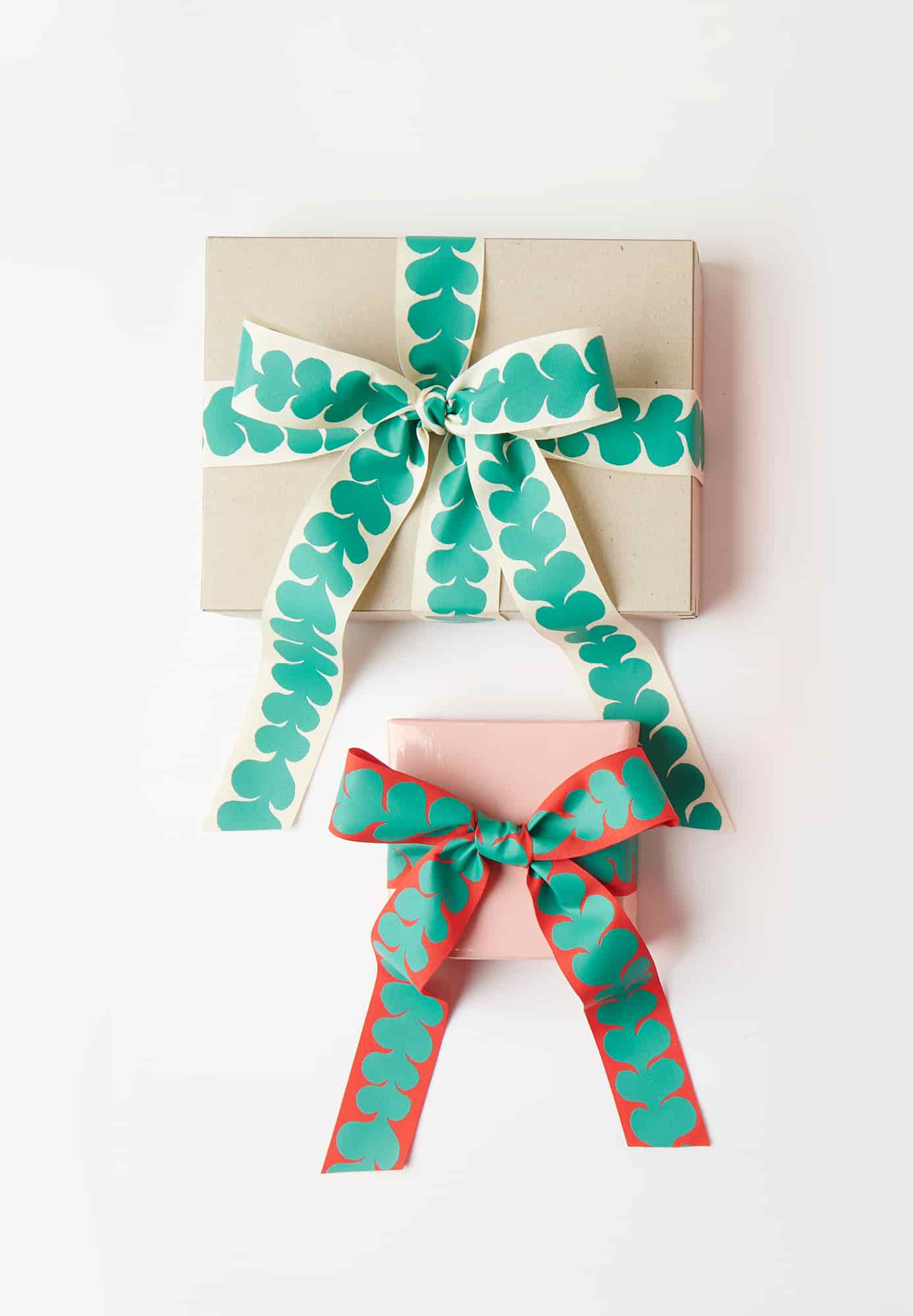 Zwei verpackte Geschenke mit grün gemusterten Schleifen auf grauem Hintergrund