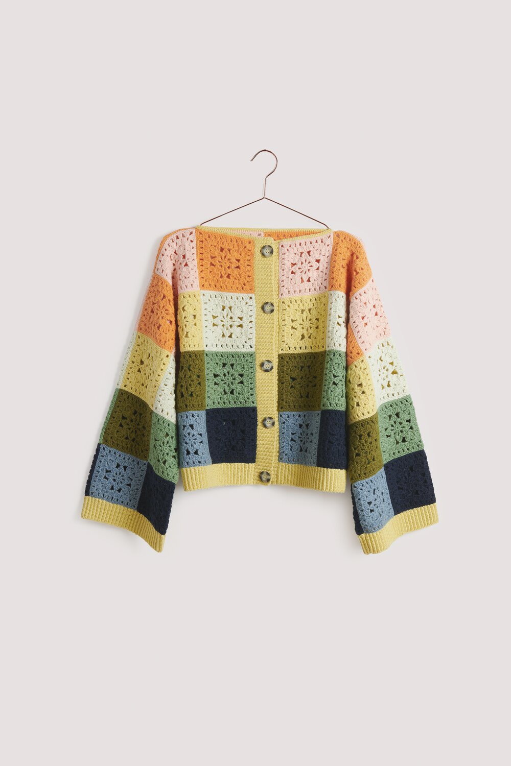 Creative Cotton Fleece dk Strickjacke mit buntem Karomuster, hängend an einem Haken. Ideal für Frühjahr-Sommer.