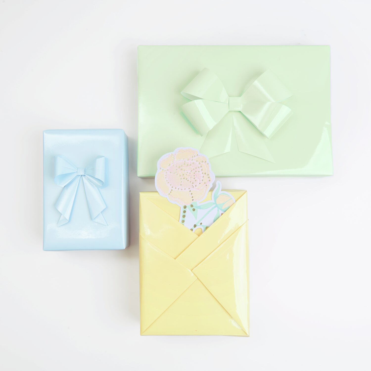 Paper Poetry Geschenkpapier Mix Lack: Drei Geschenke in Pfirsich, Hellgrün und Blaugrau mit Schleifen.