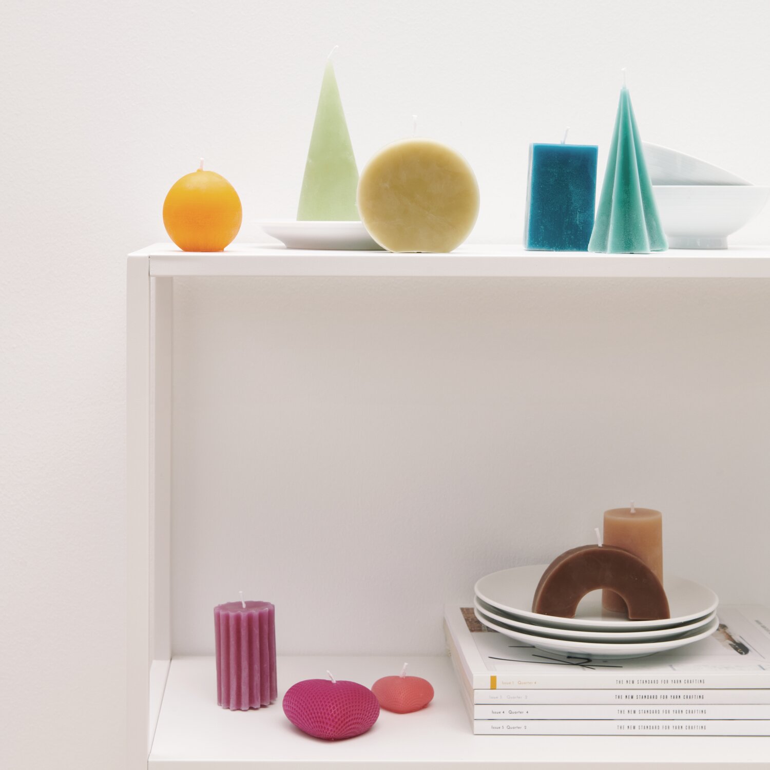 Bienenwachs Pastillen 200g von Rico Design Bienenwachs Pastillen 200g auf einem Regal mit bunten Kerzen und Geschirr, dekorativ arrangiert.