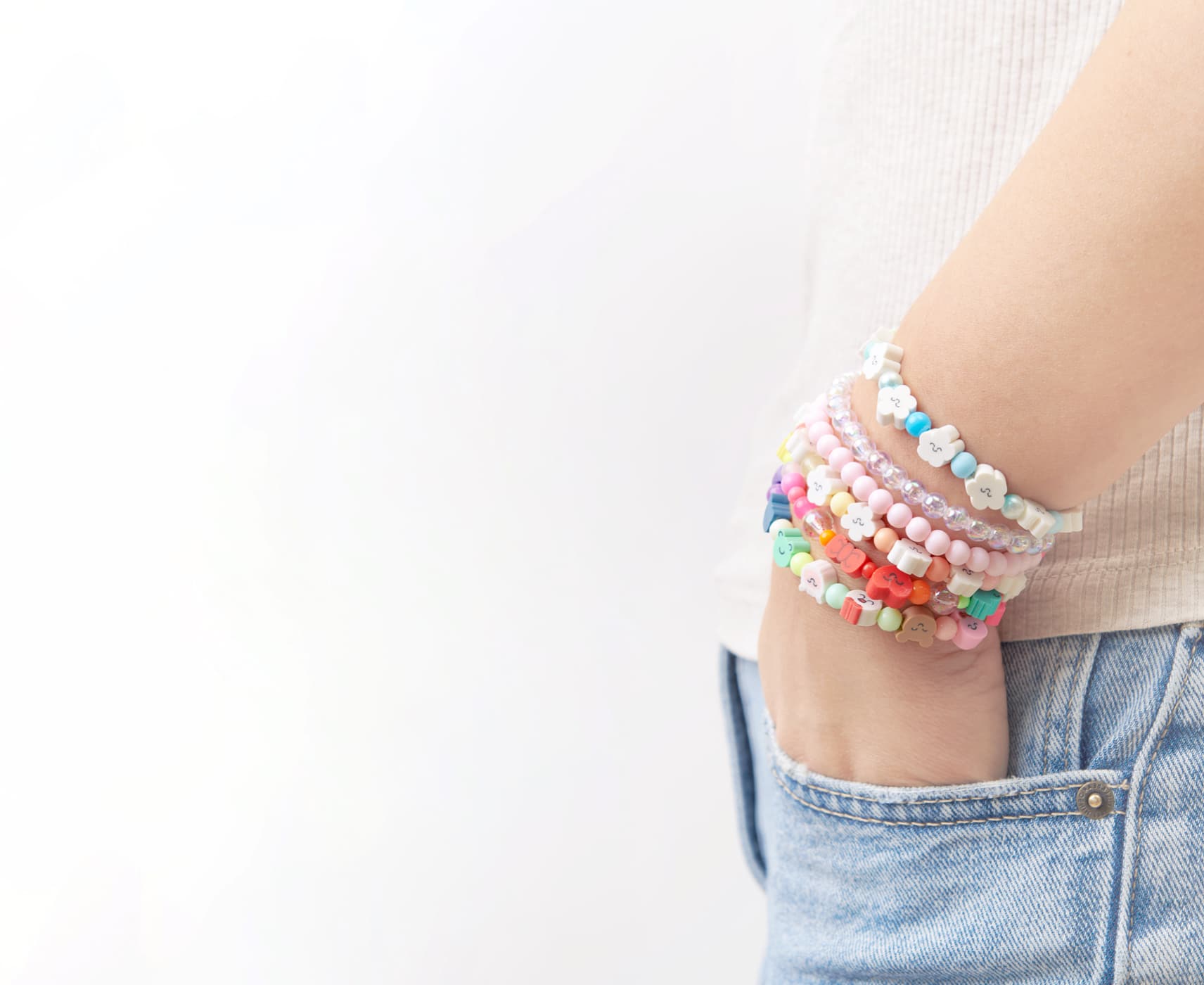 Ein Arm ist mit vielen Armbändern aus bunten Perlen geschmückt.