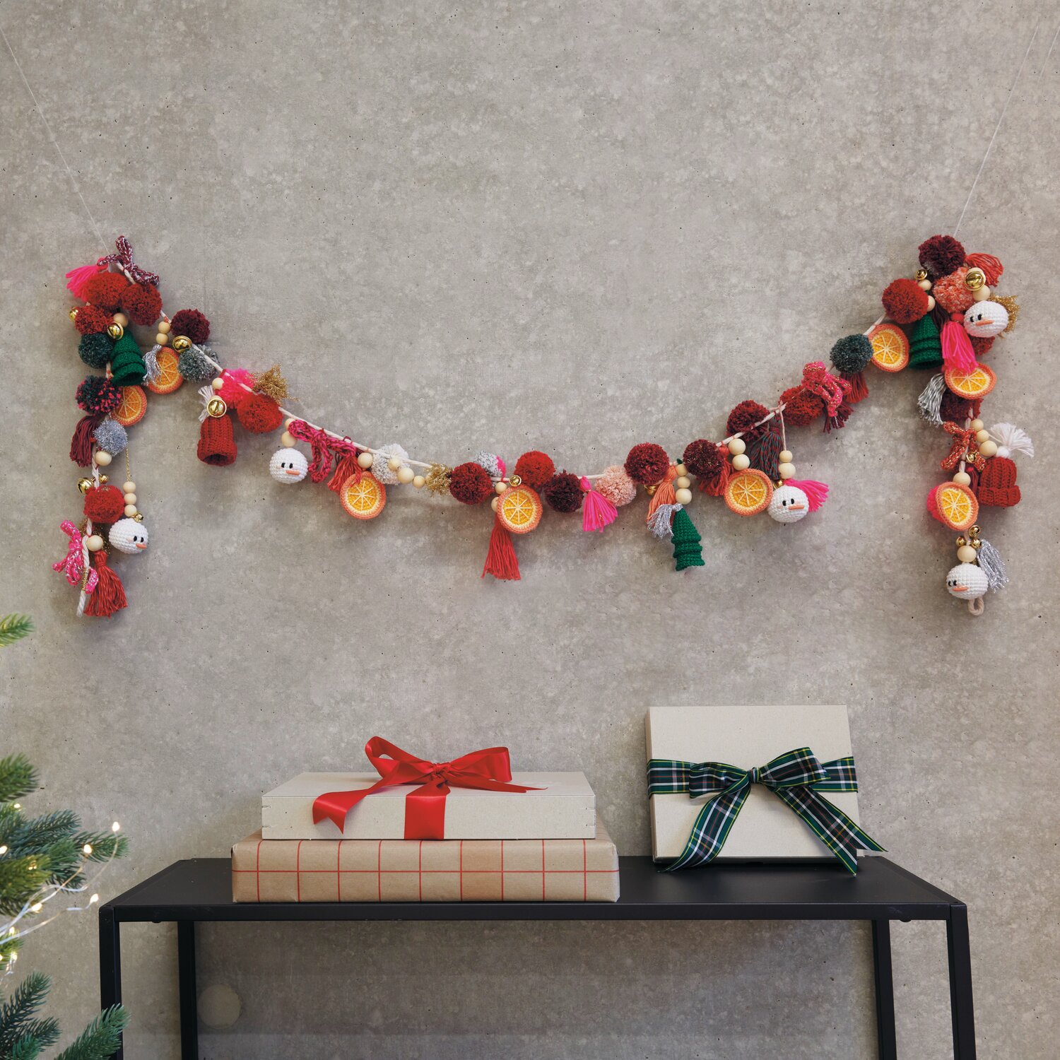 Ricorumi DIY Adventskalender von Rico Design Ricorumi DIY Adventskalender: Bunte Girlande mit Pompons und Figuren, dekorativ über Geschenken an der Wand hängend.
