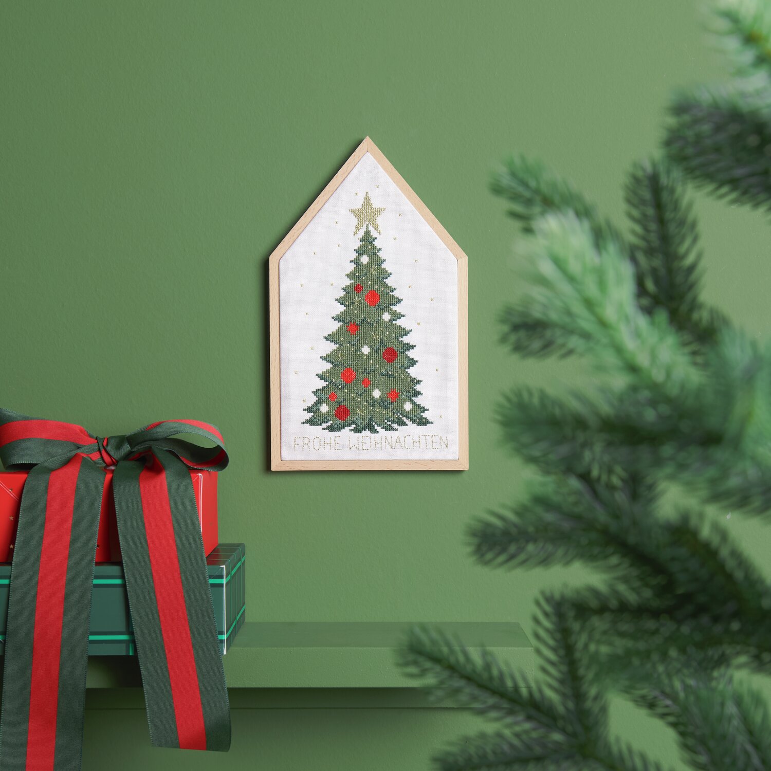 Stickpackung Weihnachtsbaum 16x27cm von Rico Design Stickpackung Weihnachtsbaum von Rico Design zeigt einen gestickten Weihnachtsbaum in einem Holzrahmen, dekoriert mit roten Kugeln und einem goldenen Stern.
