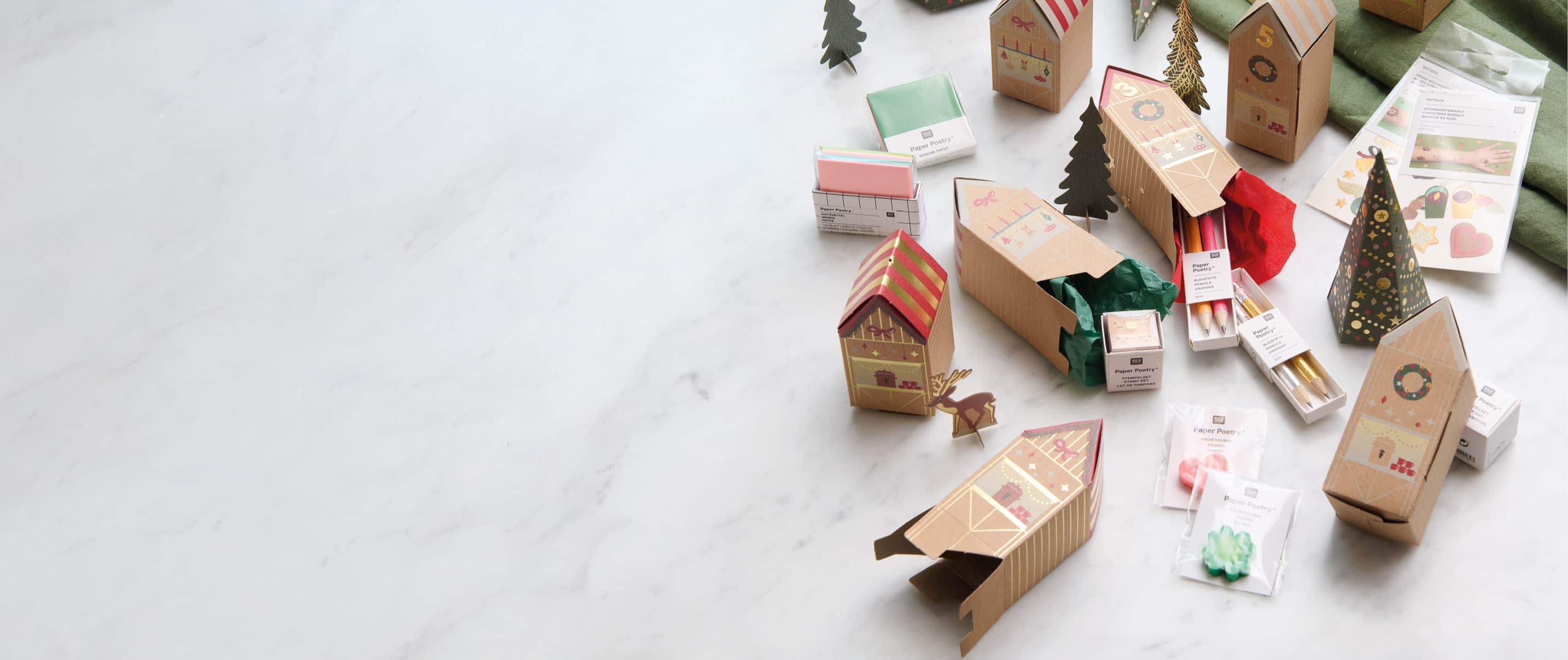 Adventskalender Häuser liegen ausgebreitet auf einem Tisch und werden mit kleinen Geschenken befüllt.