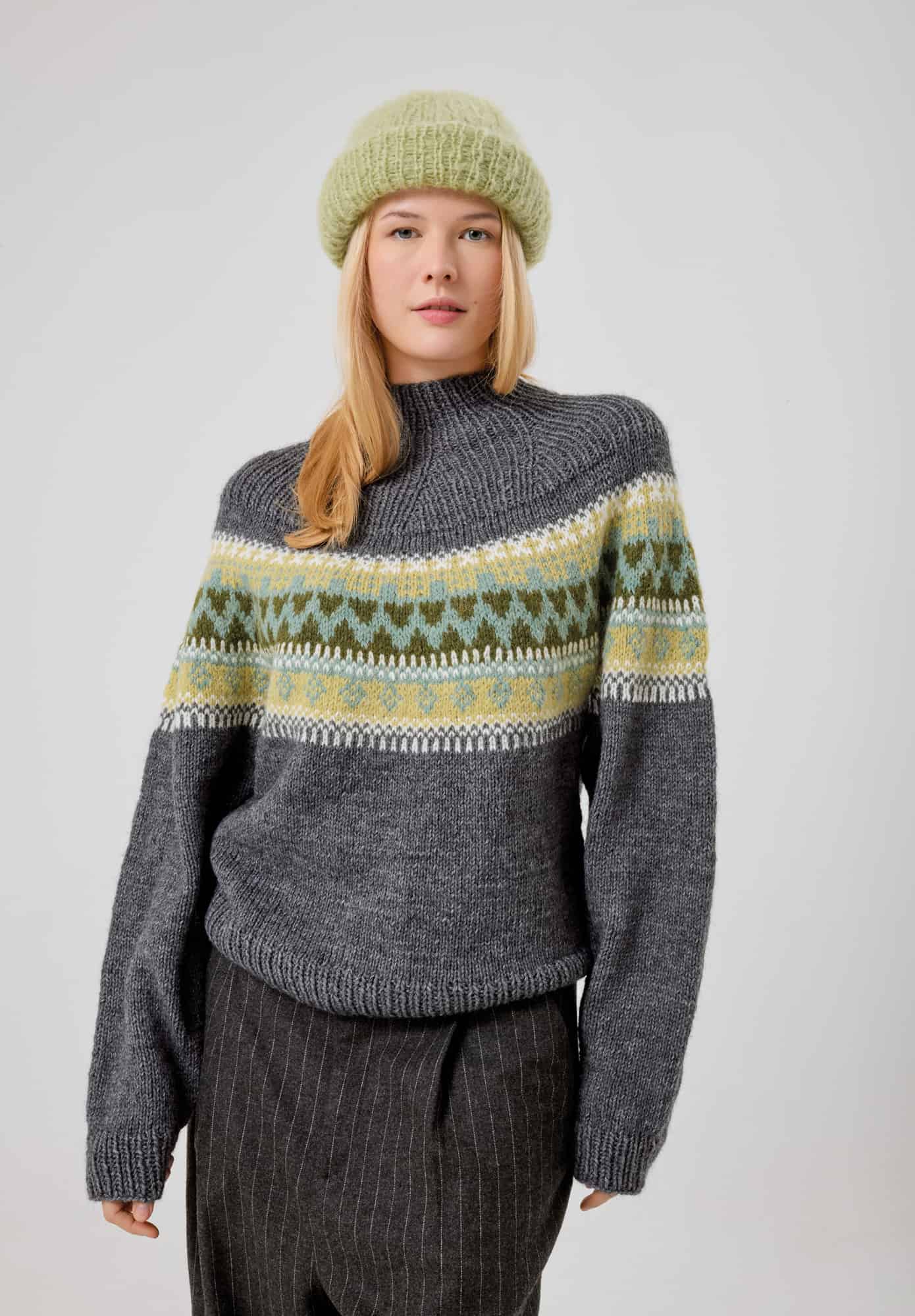 Frau trägt gestrickten grauen Pullover mit Einstrickmuster in Grüntönen: Modell 01 aus Made by Me No. 21
