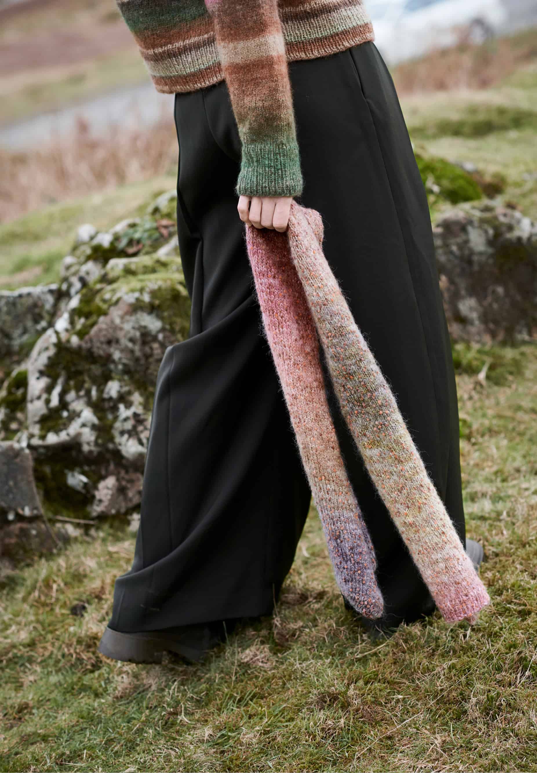 Frau hält gestrickten Schal in Pastelltönen: Modell 25 aus Lovewool No. 23
