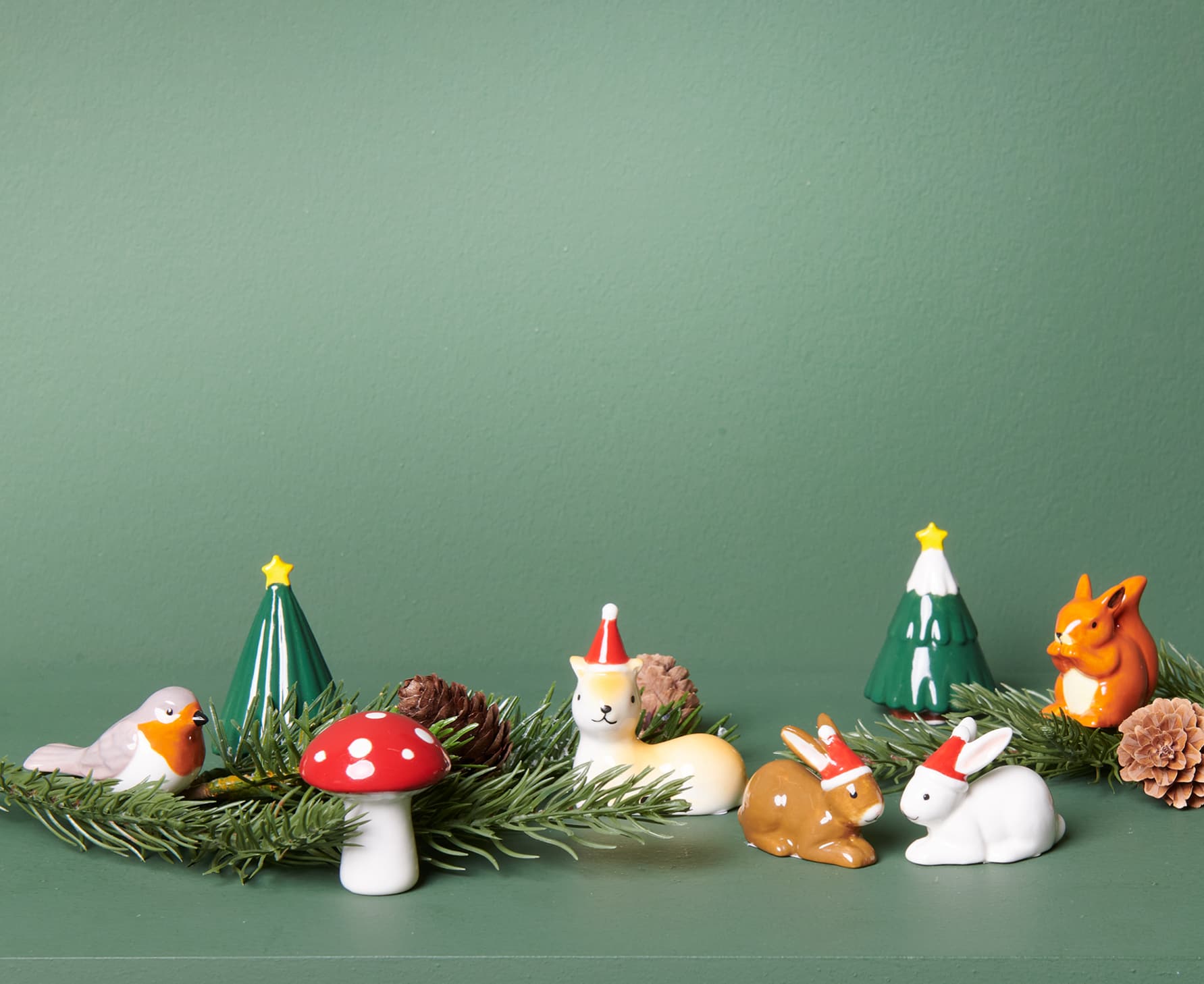 Auf einem grünen Regal sind Weihnachtsfiguren aus Porzellan dekoriert.