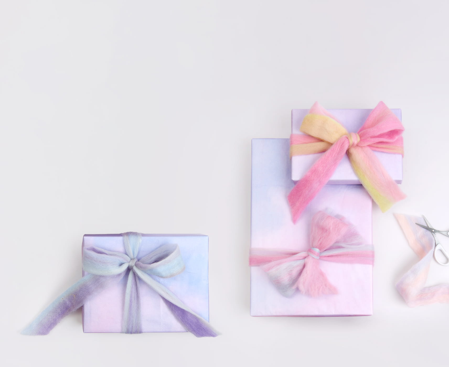 Verpackte Geschenke in Pastelltönen sind mit Filzband geschmückt. 