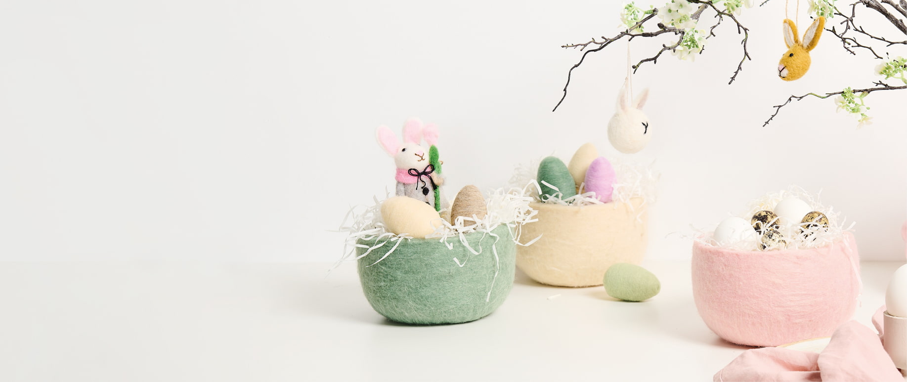 Drei Körbe aus Filz sind österlich mit Eiern und Filzfiguren dekoriert.