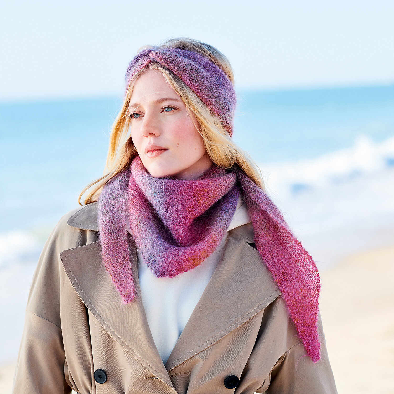 Strickanleitung Stirnband und Tuch aus Fashion Mohair Rainbows, Modell mit pastellfarbenem Stirnband und Dreieckstuch am Strand, getragen über beigem Mantel