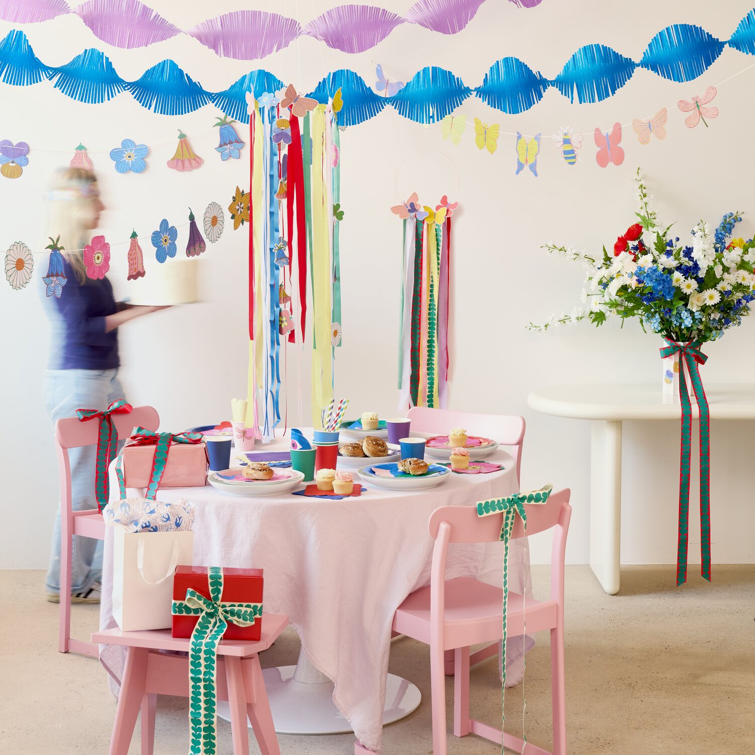 Girlande Midsommar Magic Insekten, 3m, von Rico Design schmückt fröhlich dekorierten Partytisch mit bunten Papierornamenten und festlich verpackten Geschenken.