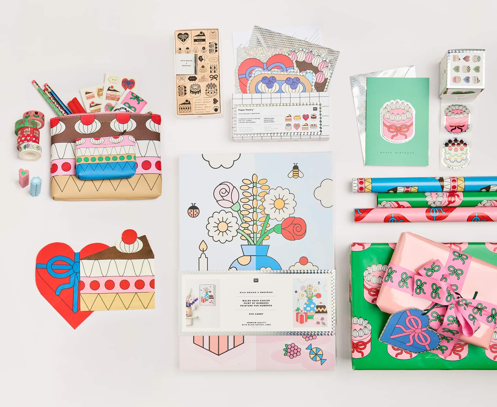 Papeterie-, Partyartikel und Etuis mit bunten Illustrationen von Torten, Schleifen und Blumen aus der Kollektion Eye Candy liegen auf grauem Hintergrund.