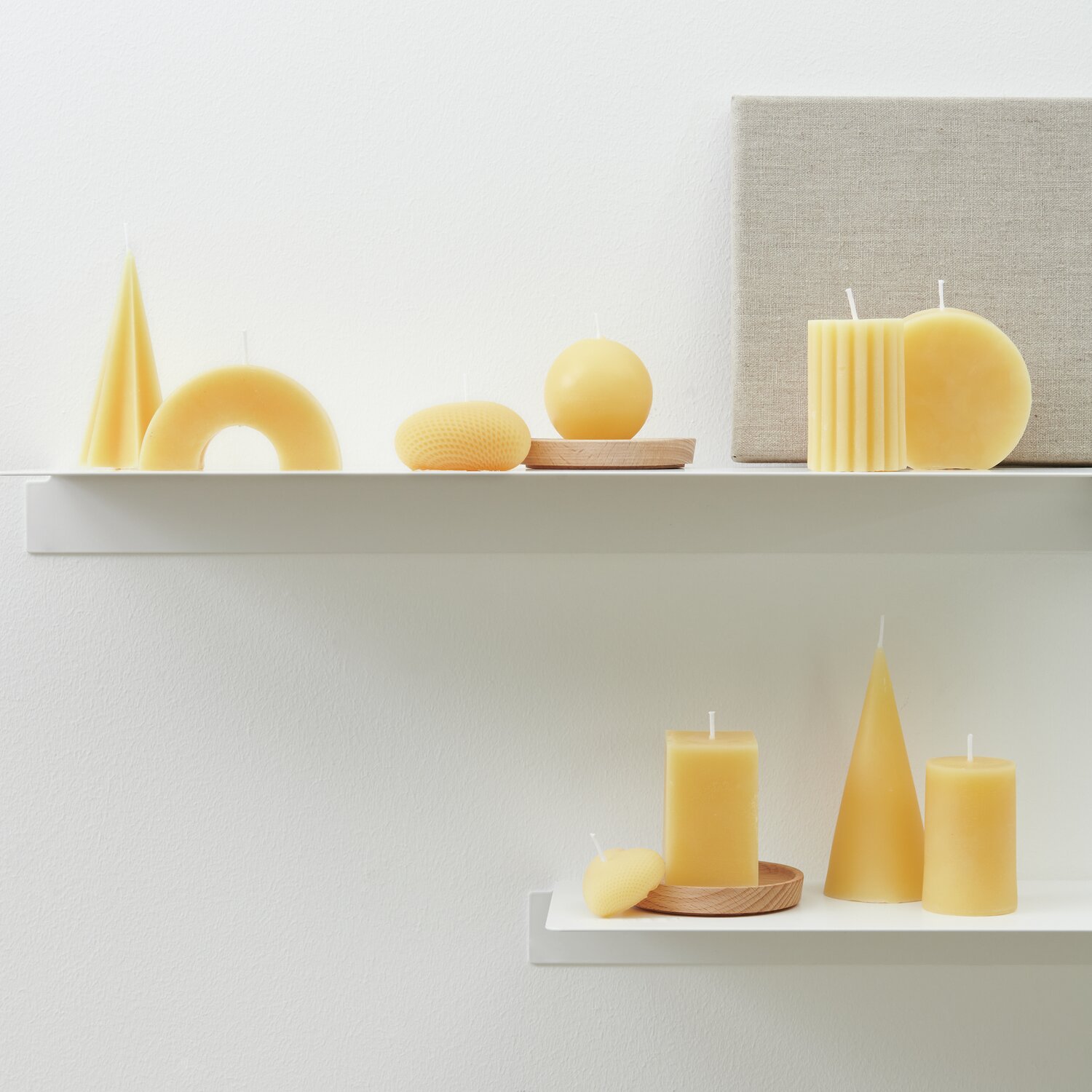 Bienenwachs Pastillen 200g von Rico Design Bienenwachs Pastillen 200g: Gelbe Kerzen in verschiedenen Formen auf weißen Regalen arrangiert.