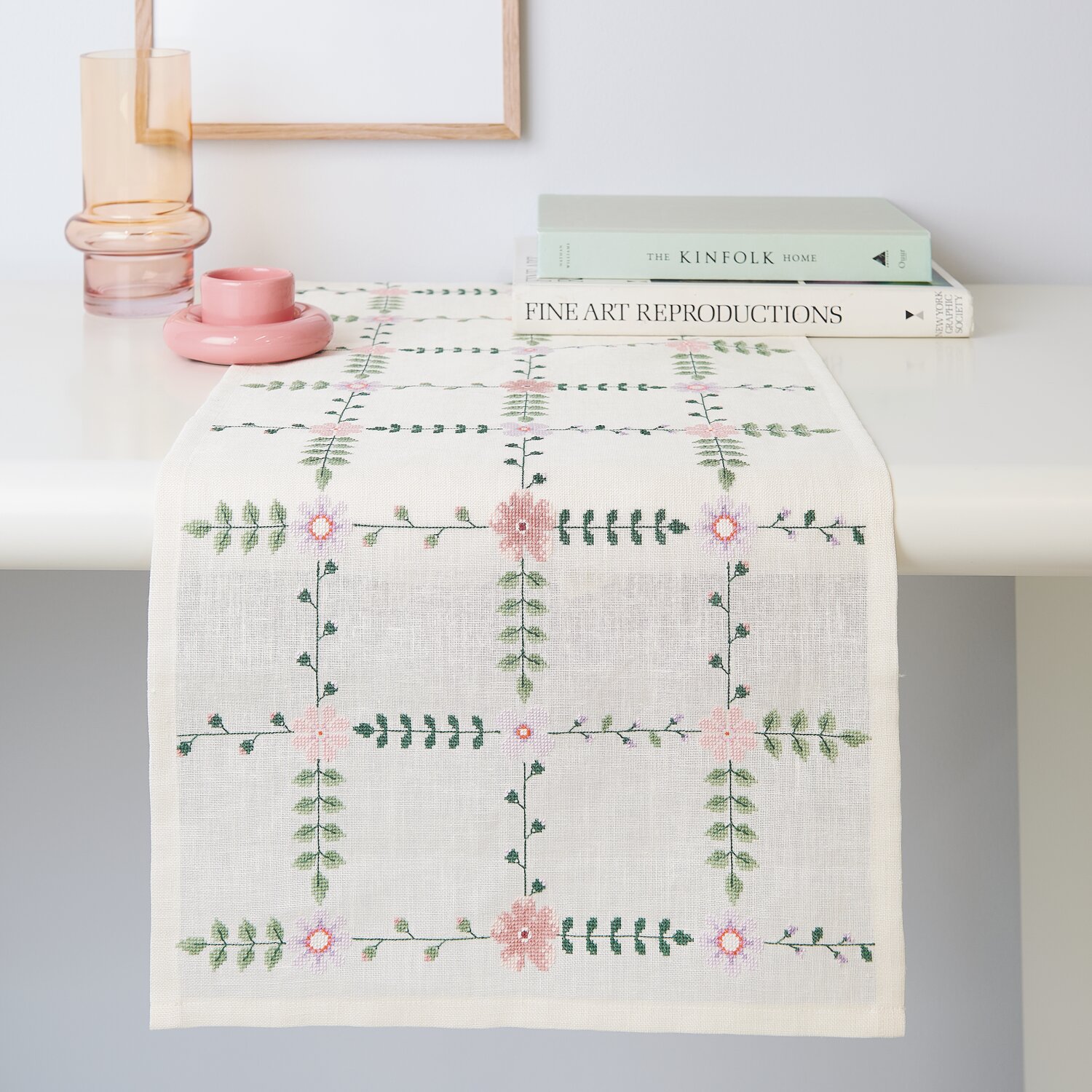 Stickpackung Gezählter Kreuzstich Tischläufer Wiesenblümchen, 42x164cm, zartes Blumenmuster auf hellem Stoff, dekorativ auf einem Tisch arrangiert.