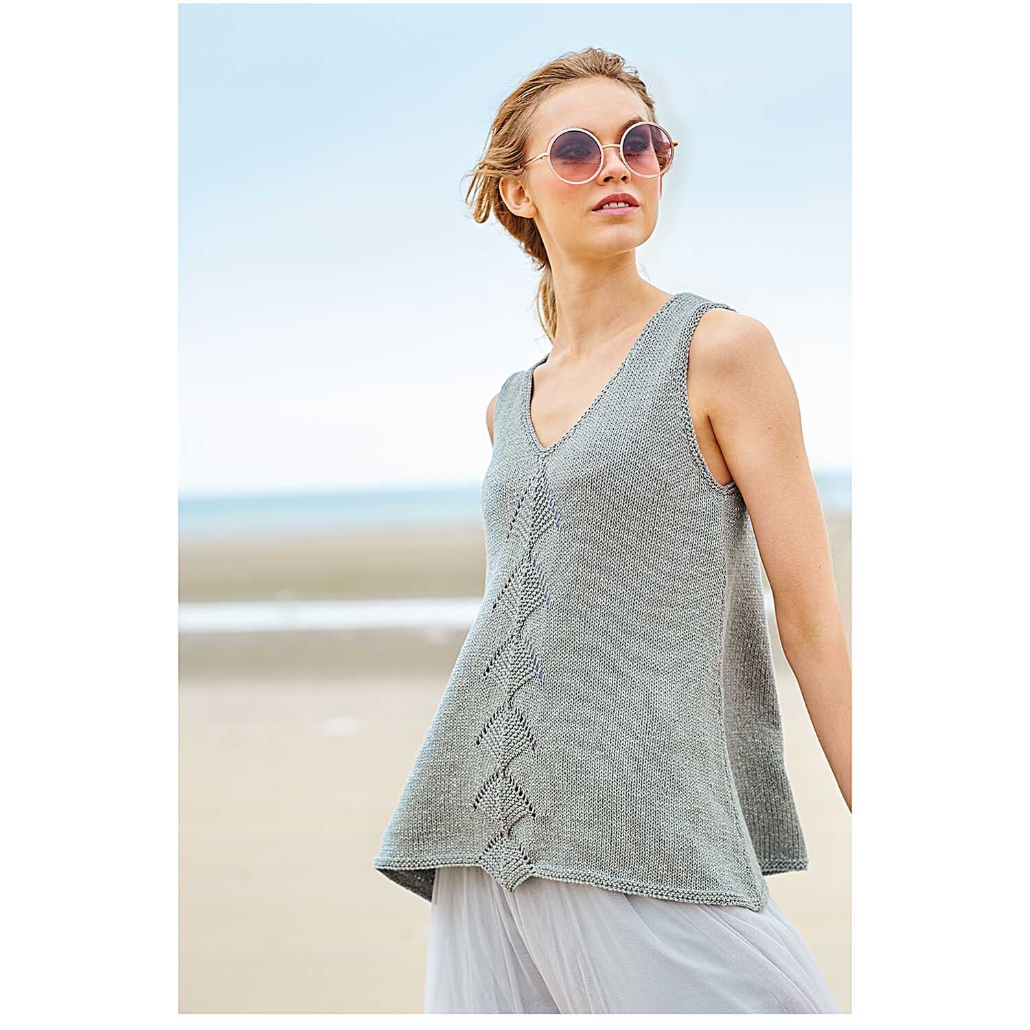 Fashion Cotton Métallisé dk: Frau am Strand in grauem ärmellosen Oberteil von Rico Design, mit Sonnenbrille.