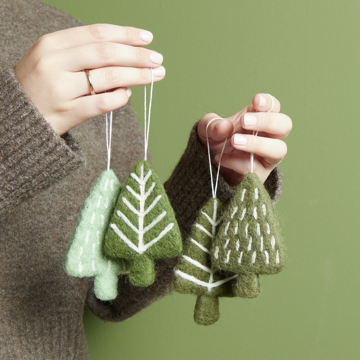 Aufhänger Tanne mit Tannenzapfen handgefilzt, in Mint und Khaki, von Rico Design, gehalten von einer Hand.