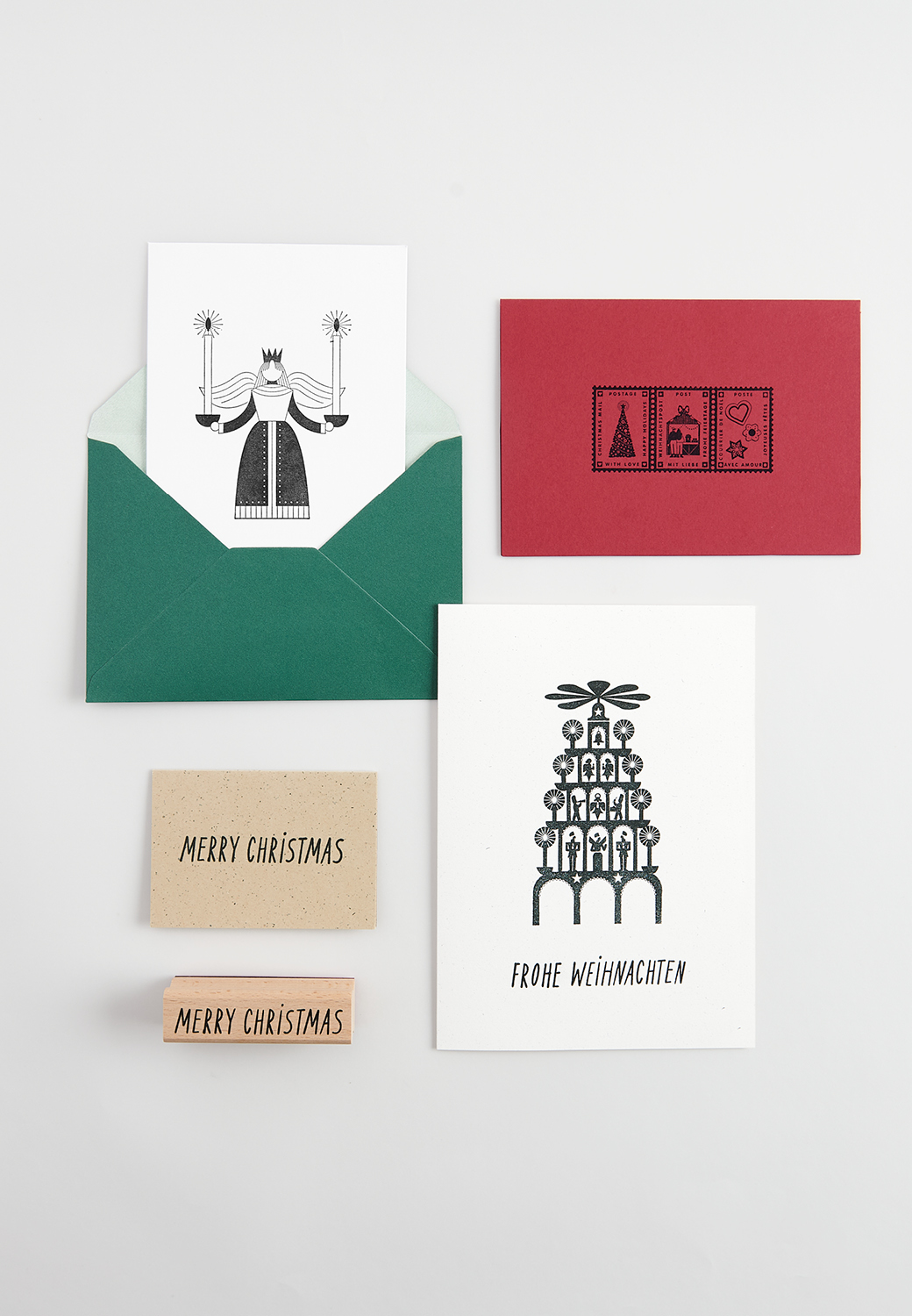 Weihnachtlich bestempelte Postkarten und Umschläge liegen zusammen mit Holzstempel auf grauem Hintergrund 