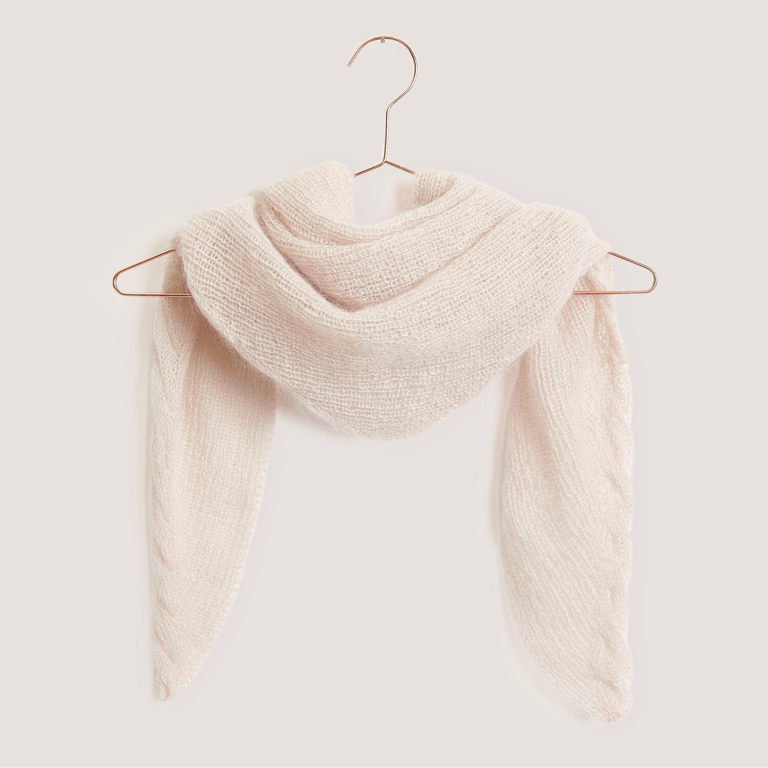 Strickset Dreieckstuch Modell 04 aus Tücher Special aus Essentials Super Kid Mohair Loves Silk Glamorous Glitter von Rico Design Strickset Dreieckstuch Modell 04 aus weichem Mohair-Seide-Garn in Natur auf einem Kleiderbügel.