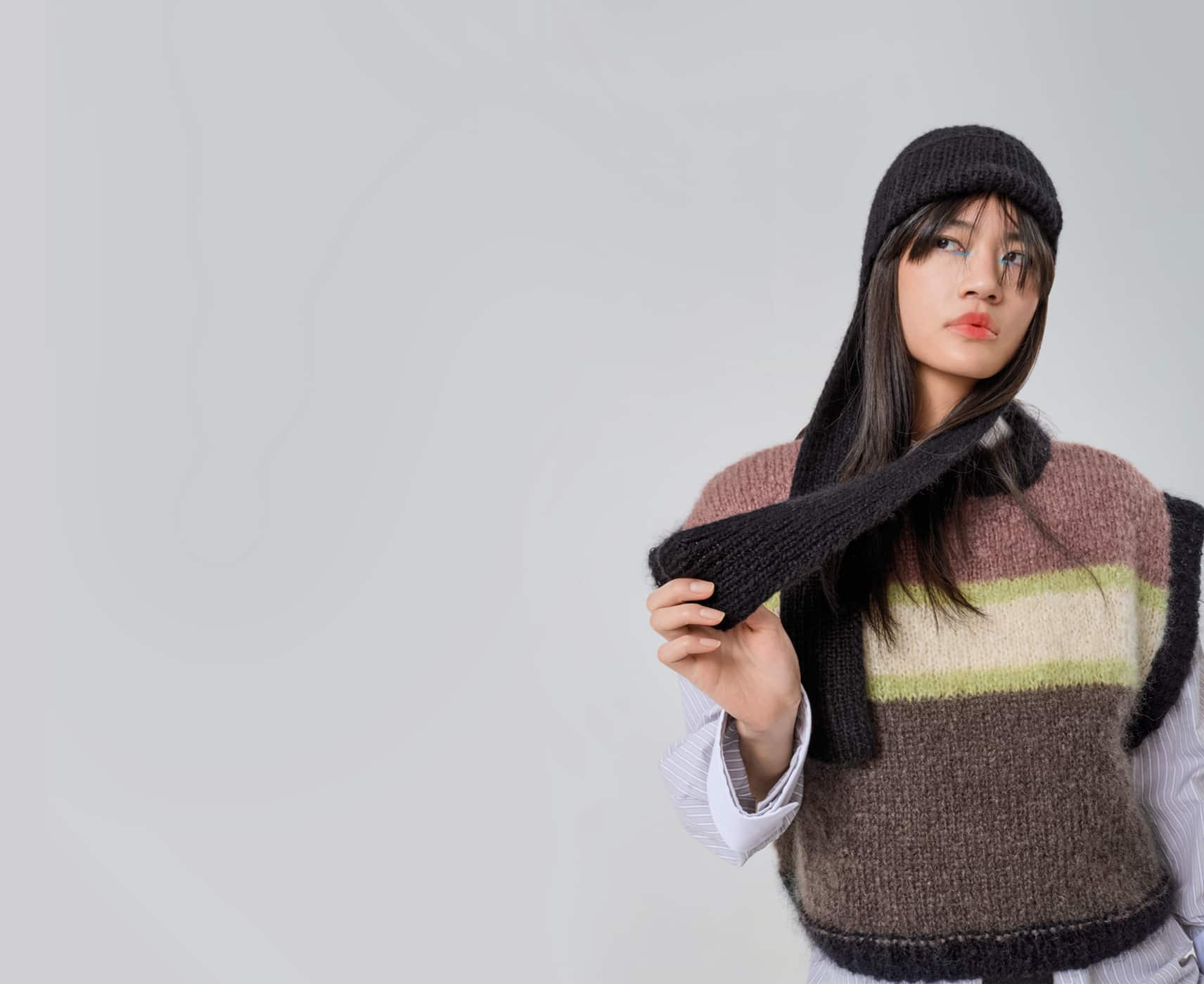 Eine Frau trägt gestrickten Pullunder und eine gestrickte Mütze mit Ohrenklappen