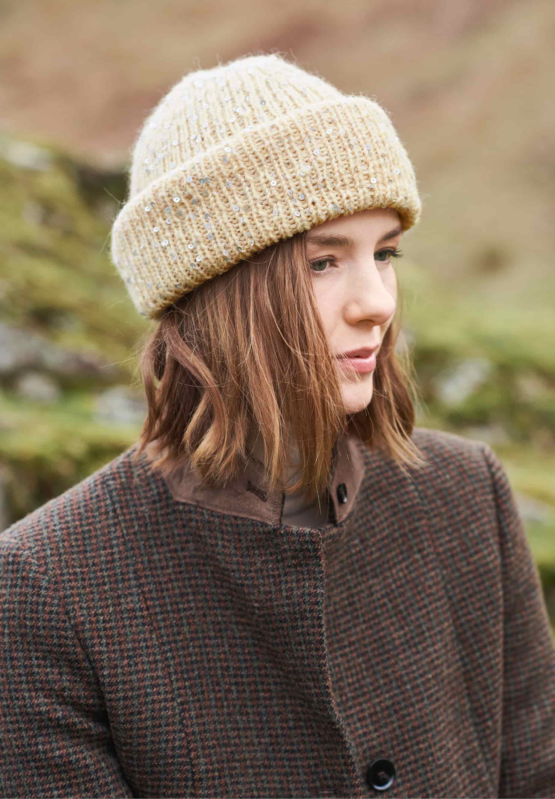 Frau trägt eine gestrickte Mütze in Creme mit Pailletten: Modell 03 aus Lovewool No. 23