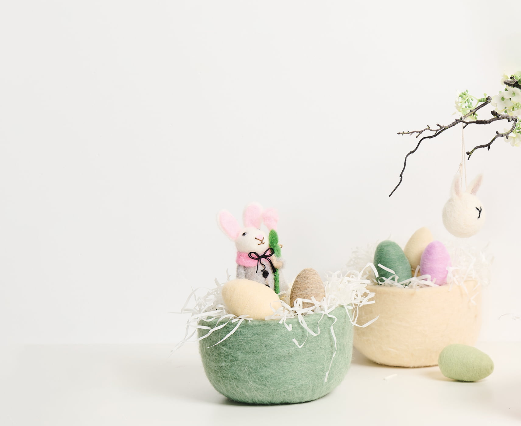 Zwei Körbe aus Filz sind österlich mit Eiern und Filzfiguren dekoriert.