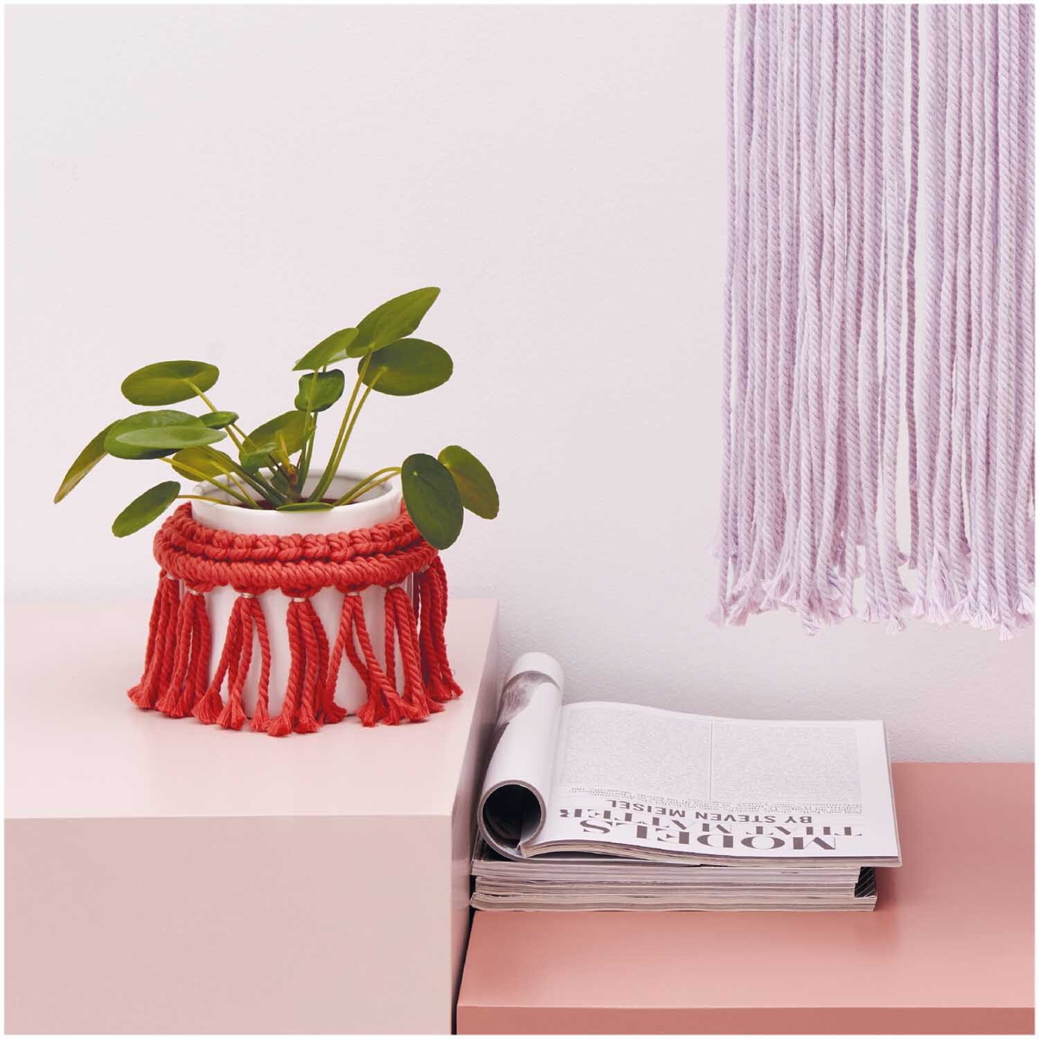 Creative Cotton Cord Makramee-Garn in Rot, dekoriert als Pflanzenhalter neben einem Magazin auf einem Tisch. Ideal für kreative DIY-Projekte.