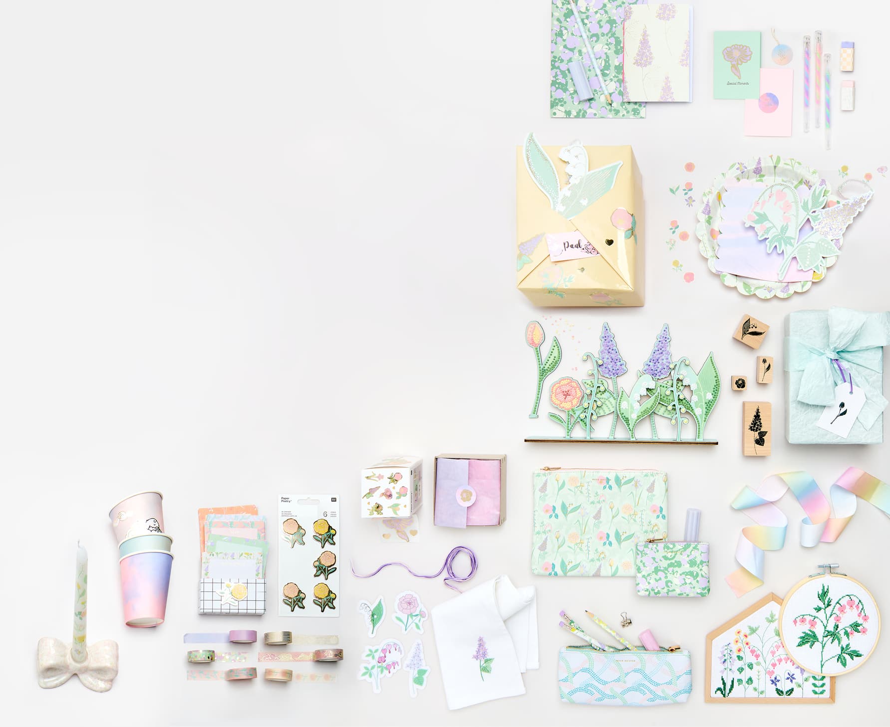 Papeterie-, Party und Geschenkprodukte mit Himmel- und Blumendesigns liegen angeordnet auf grauem Hintergrund.