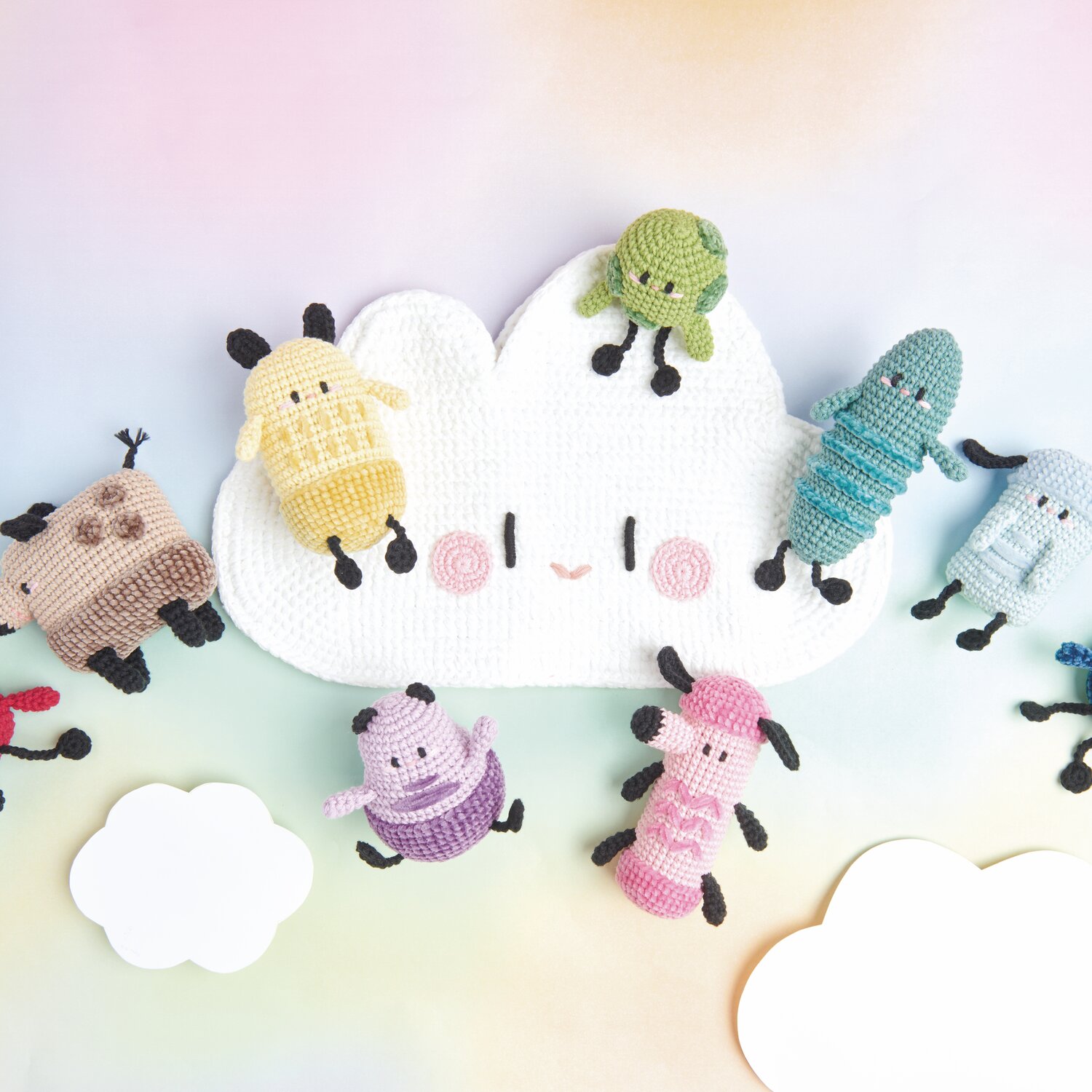 Ricorumi Rainbow Weirdos: Bunte, gehäkelte Figuren von Rico Design auf einer weißen Wolke arrangiert.
