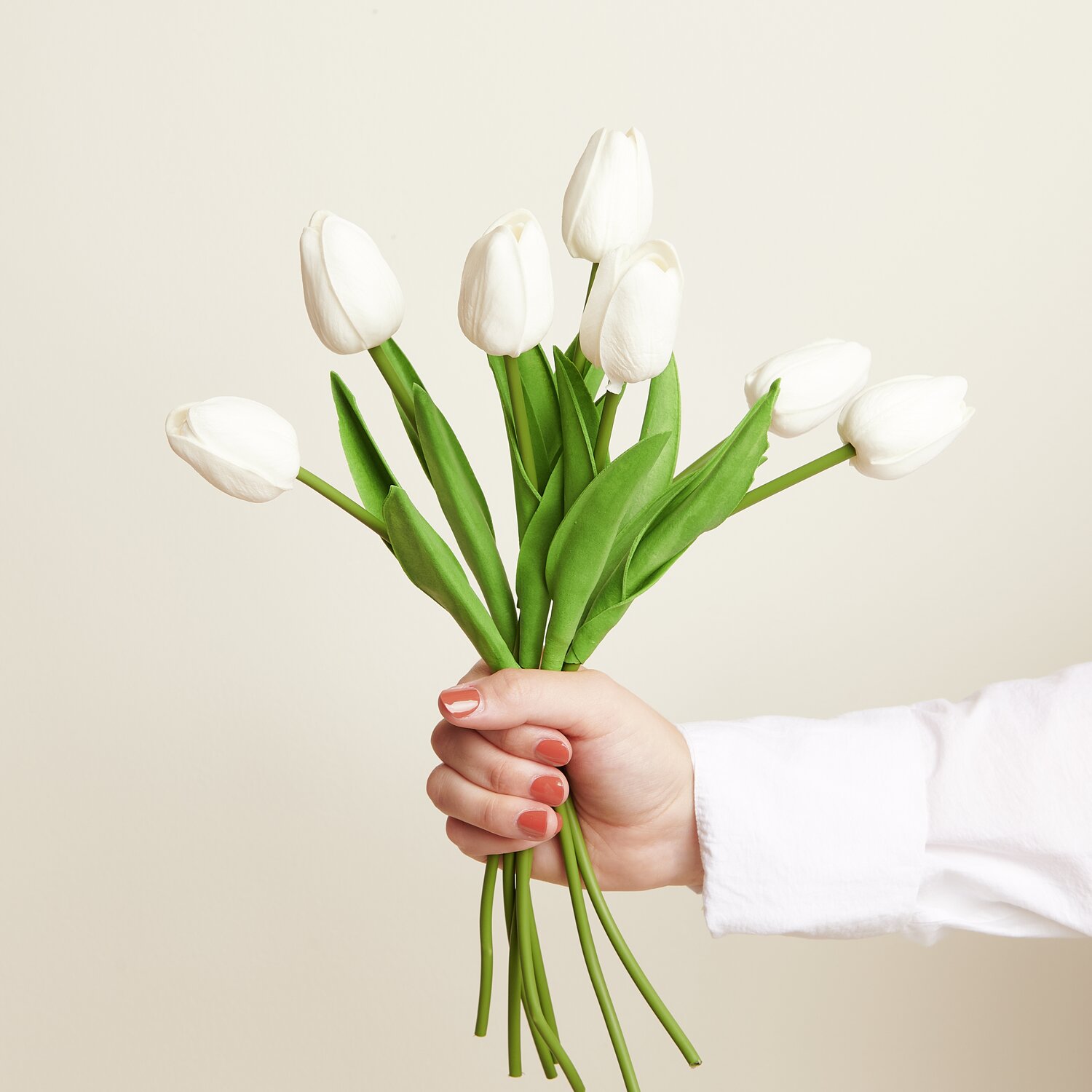 Tulpenstrauß mit 7 Blüten, weiß, 33,5cm. Eine Hand hält die eleganten Blumen vor einem neutralen Hintergrund.