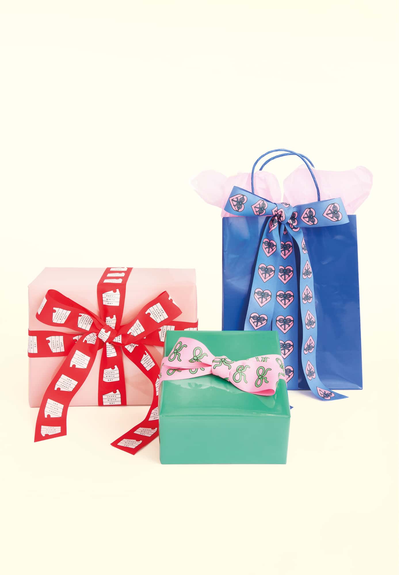 Geschenktüten und verpackte Geschenke in blau, grün und rot stehen vor gelbem Hintergrund. 