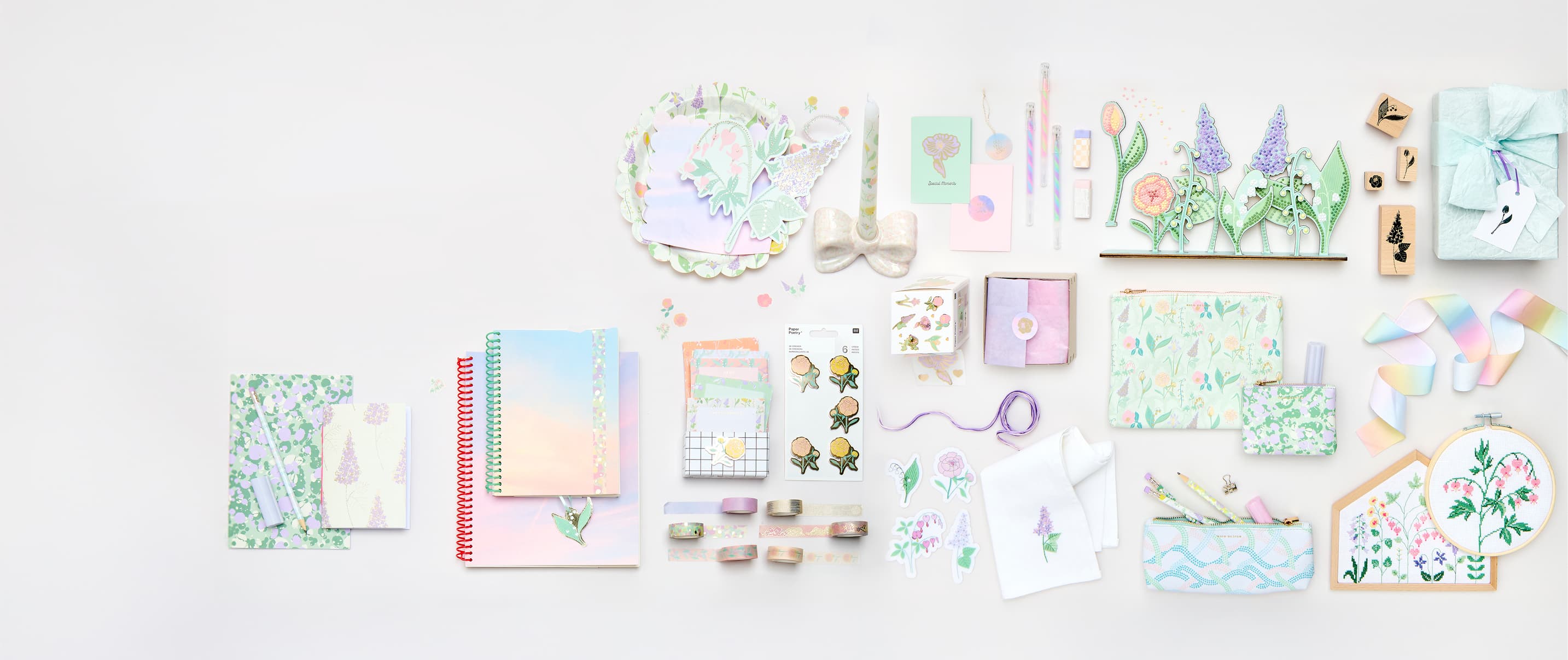 Papeterie-, Party und Geschenkprodukte mit Himmel- und Blumendesigns liegen angeordnet auf grauem Hintergrund.