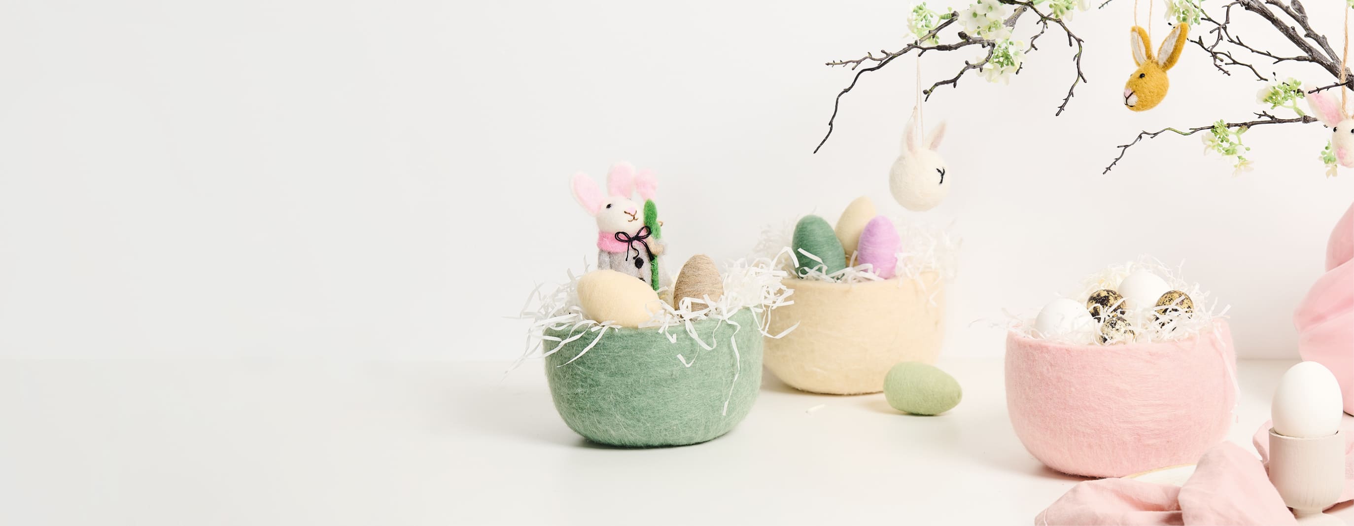 Drei Körbe aus Filz sind österlich mit Eiern und Filzfiguren dekoriert.