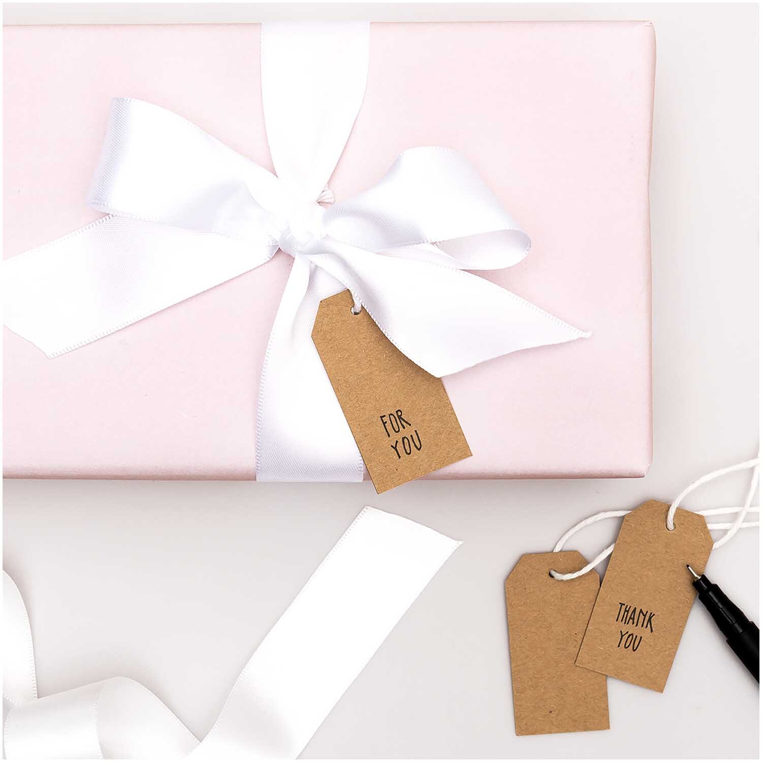 Paper Poetry Papieranhänger Kraftpapier 24 Stück, braun, an rosa Geschenk mit weißer Schleife.