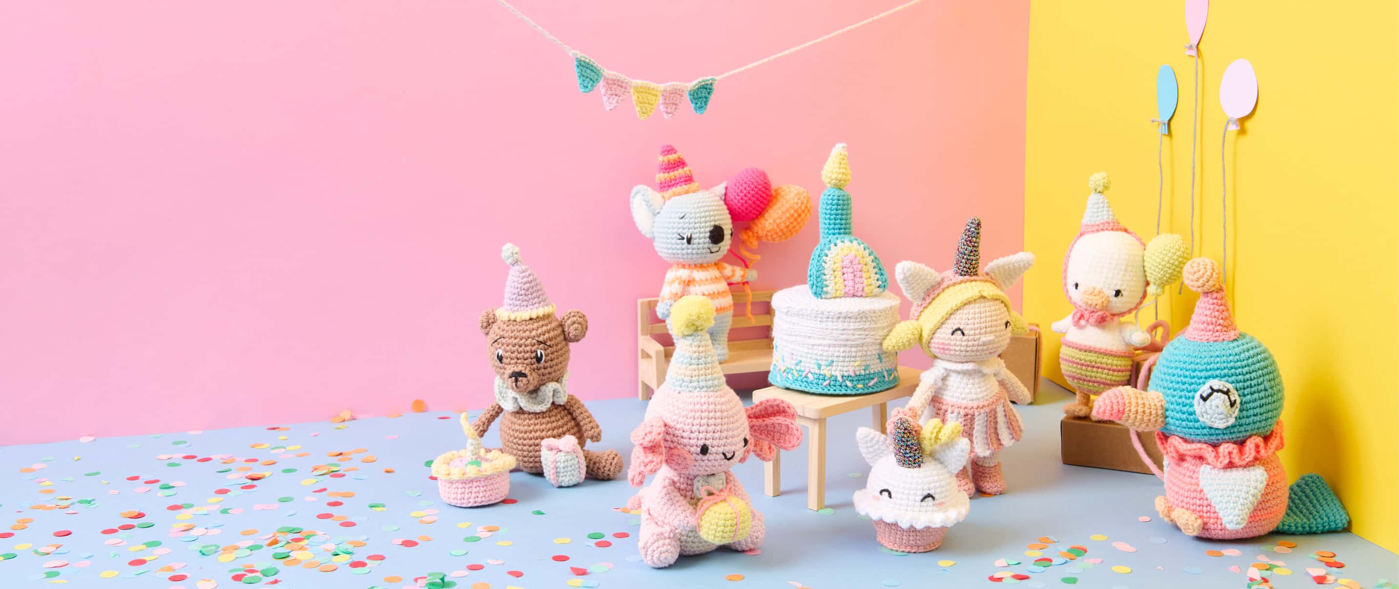Sieben Amigurumis zum Thema Birthday Party sind mit Partyaccessoires vor bunten Wänden dekoriert. 