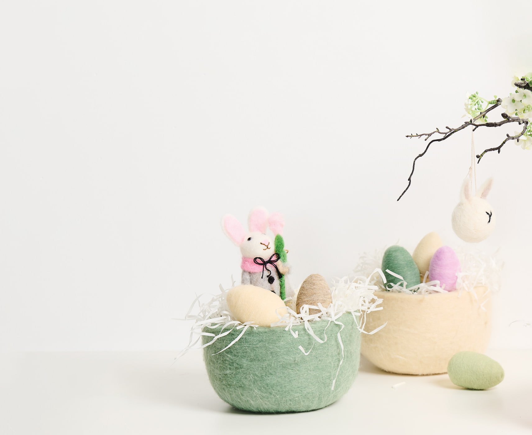 Zwei Körbe aus Filz sind österlich mit Eiern und Filzfiguren dekoriert.