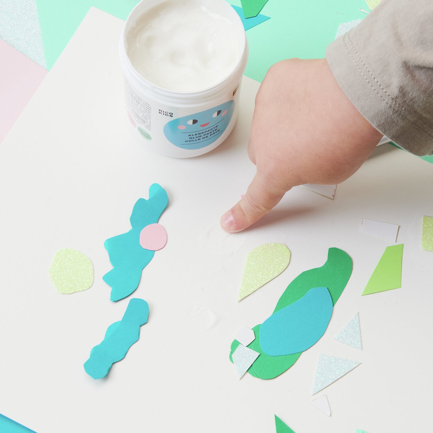 Kinder Klebepaste U3, 150g: Ein Kind verwendet weiße Paste von Rico Design zum Basteln mit buntem Papier.