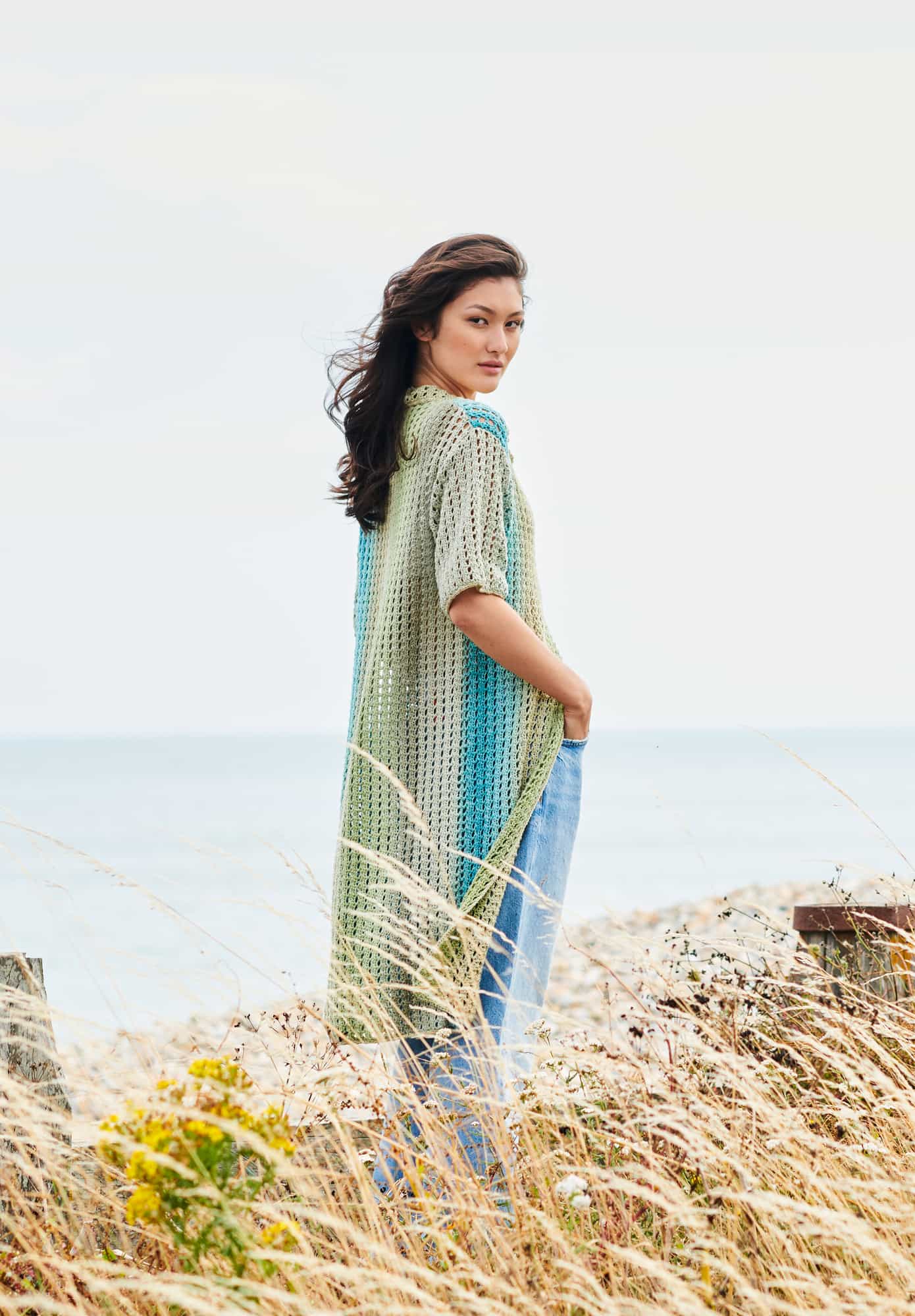 Frau trägt gehäkeltes Hemdkleid in Grün und Blautönen: Modell 25 aus Lovewool No. 22