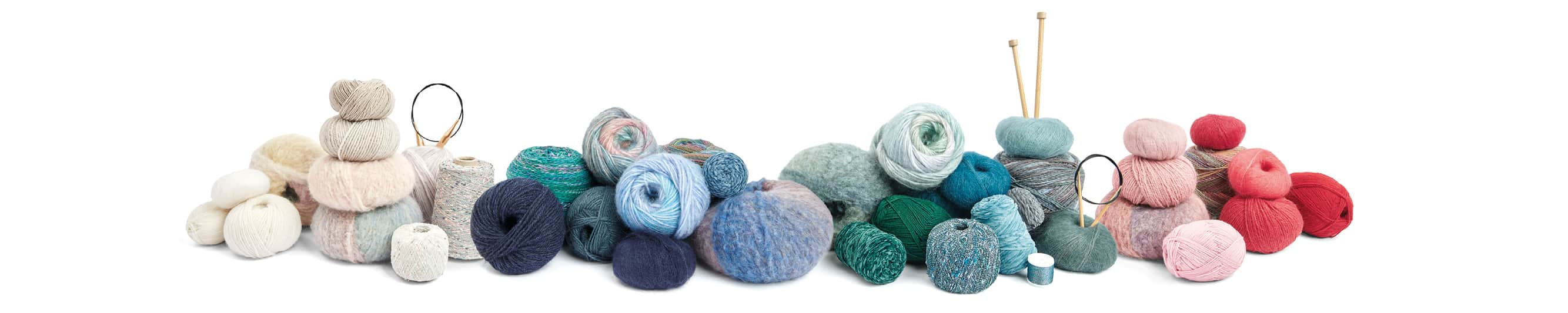 Wollknäuel in verschiedenen Farben aneinandergereiht. Teilweise stecken Stricknadeln in den Garnknäueln