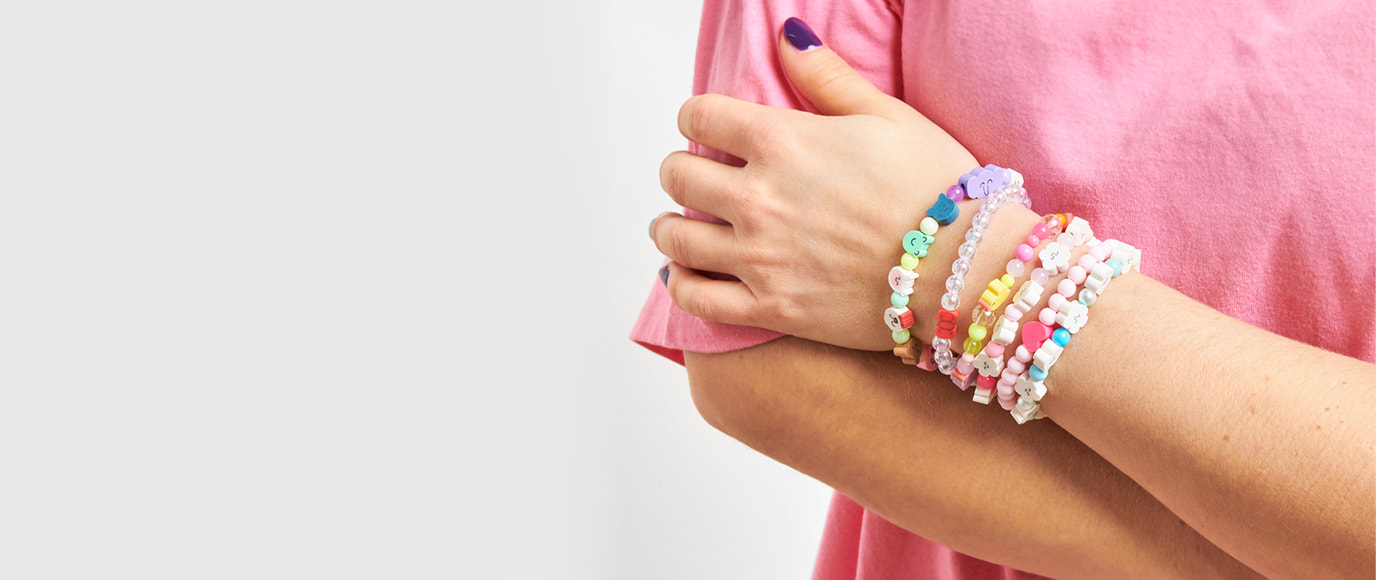 Ein Arm ist mit vielen Armbändern aus bunten Perlen geschmückt.