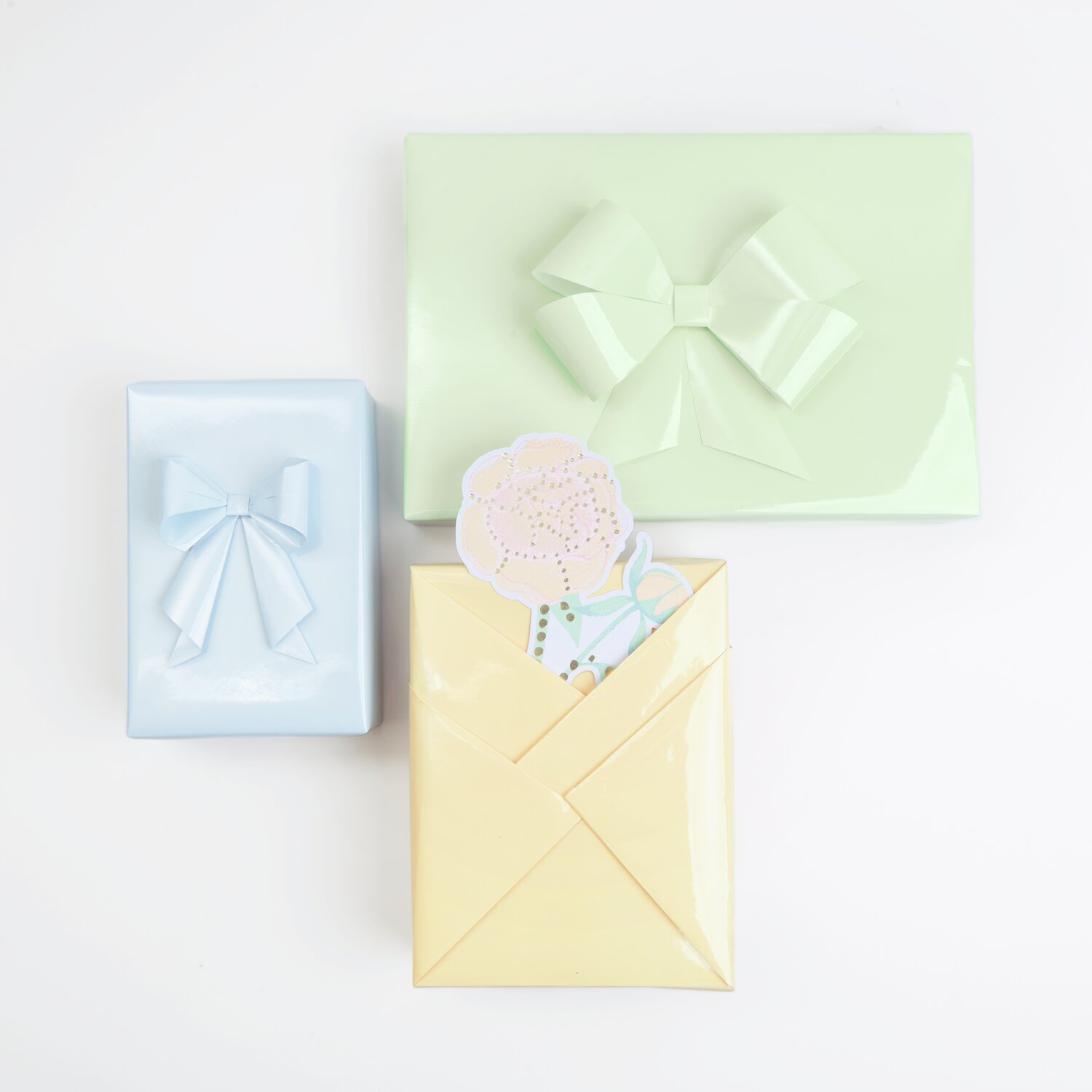 Paper Poetry Geschenkpapier Mix Lack: Drei Geschenke in Pfirsich, Hellgrün und Blaugrau mit Schleifen.