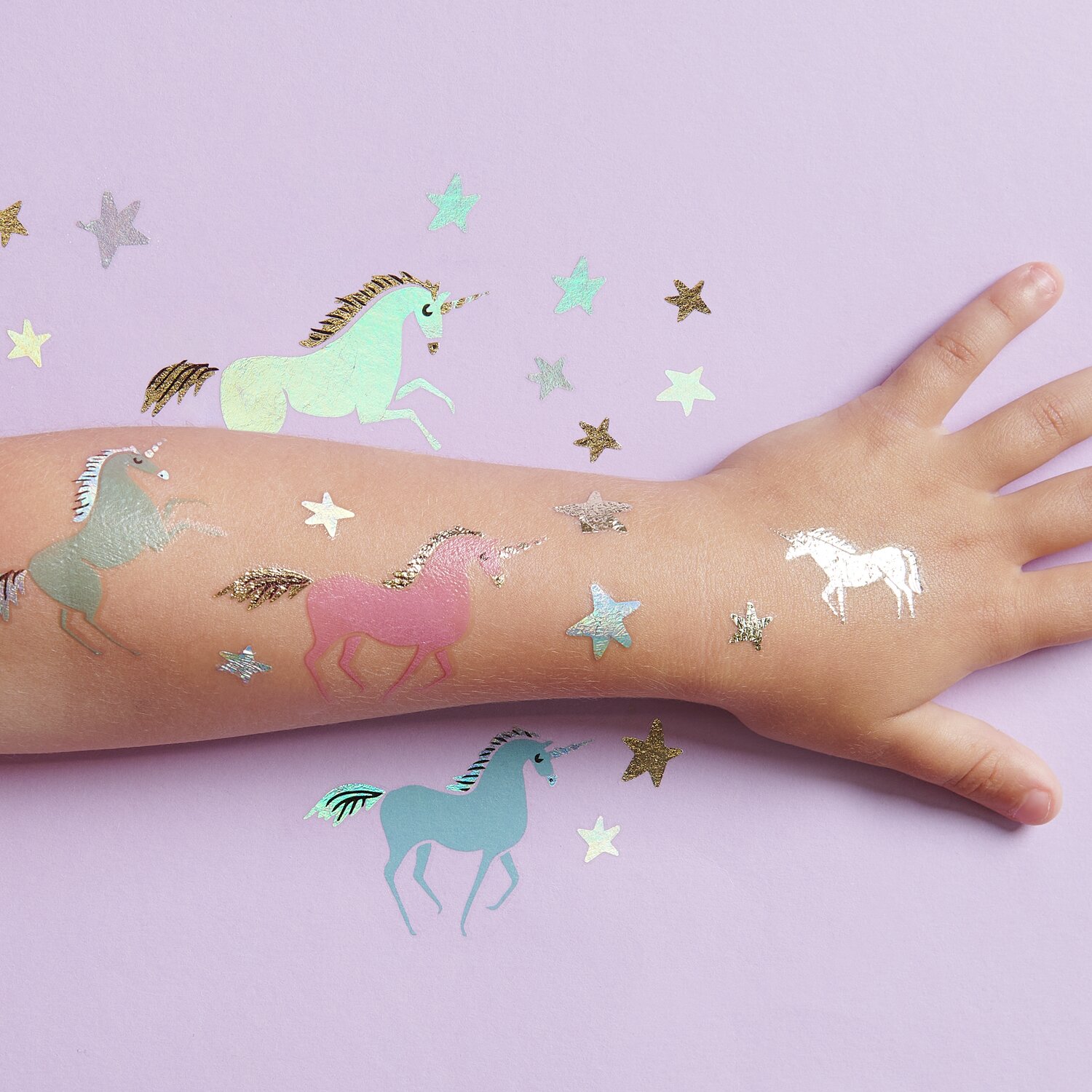 Tattoos Einhörner: 27-teiliges Set mit bunten Einhorn- und Sternmotiven auf Kinderarm.
