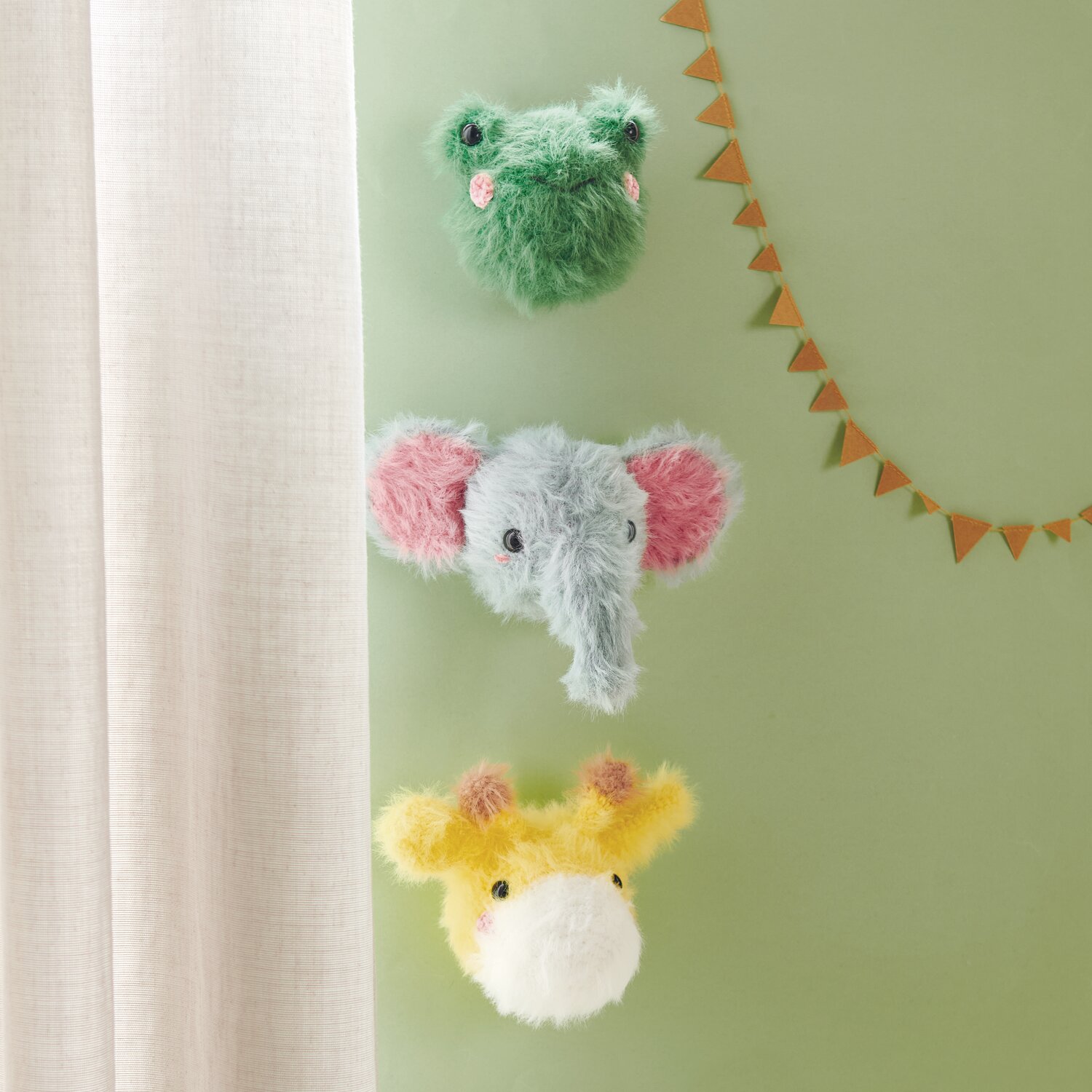 Ricorumi Furry Animals: Drei gehäkelte Tierköpfe in Grün, Blau und Gelb an einer grünen Wand.